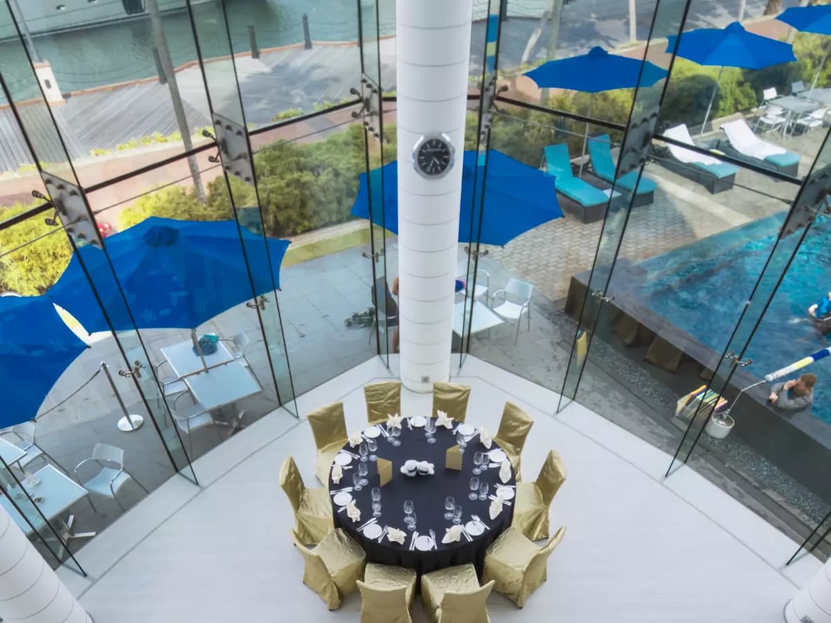 Round dining table setup with gold chairs overlooking waterfront patio.