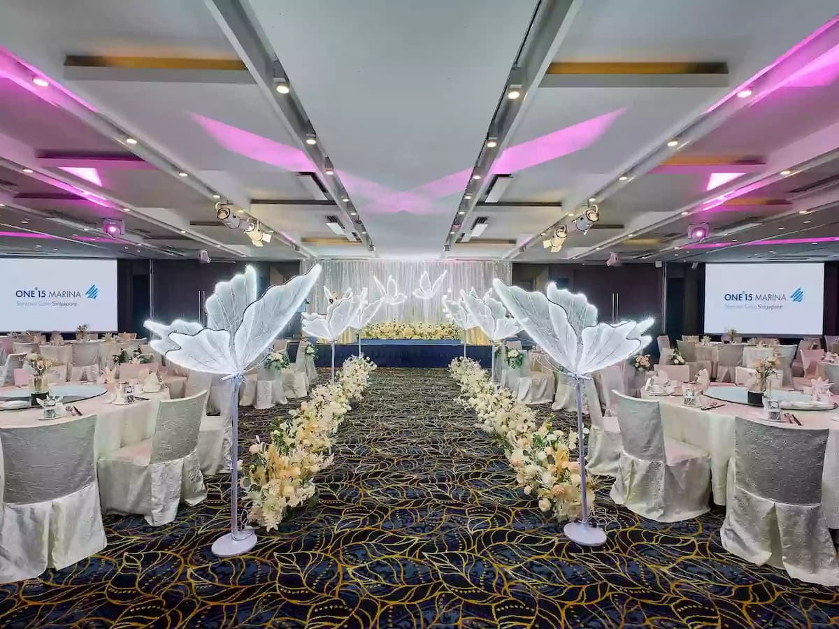 Wedding banquet hall with illuminated aisle décor and elegant table settings.