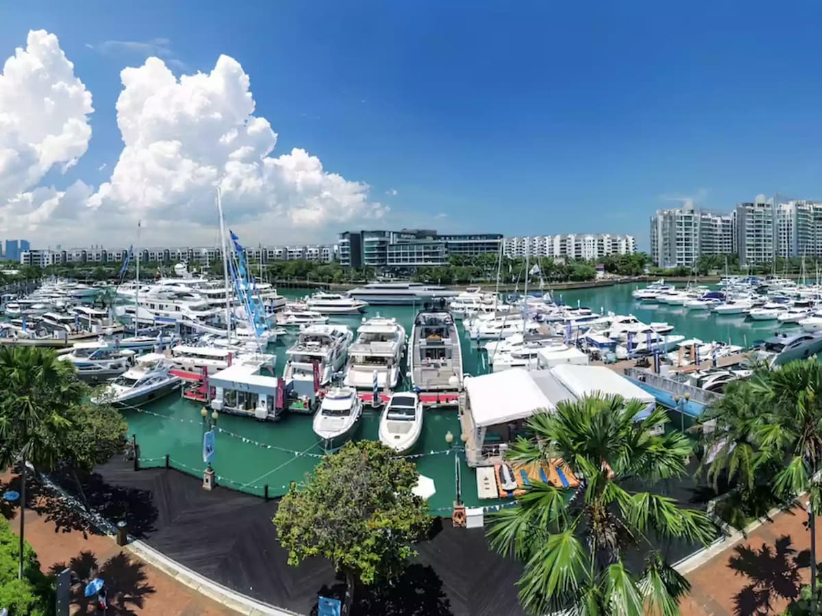 Marina view with yachts docked along the waterfront under blue skies.