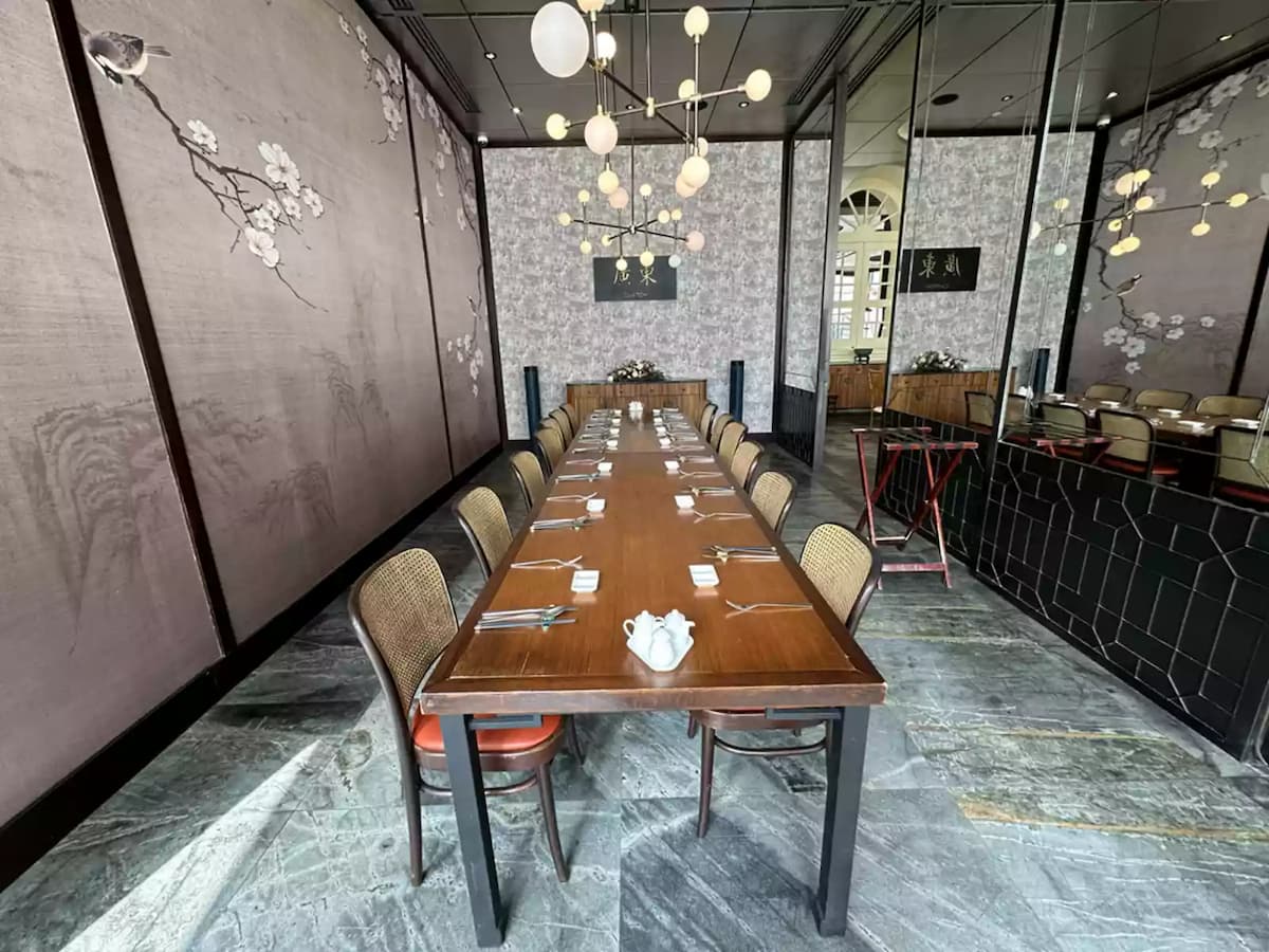 Private dining room with long table, mirrored wall, and pendant lights.