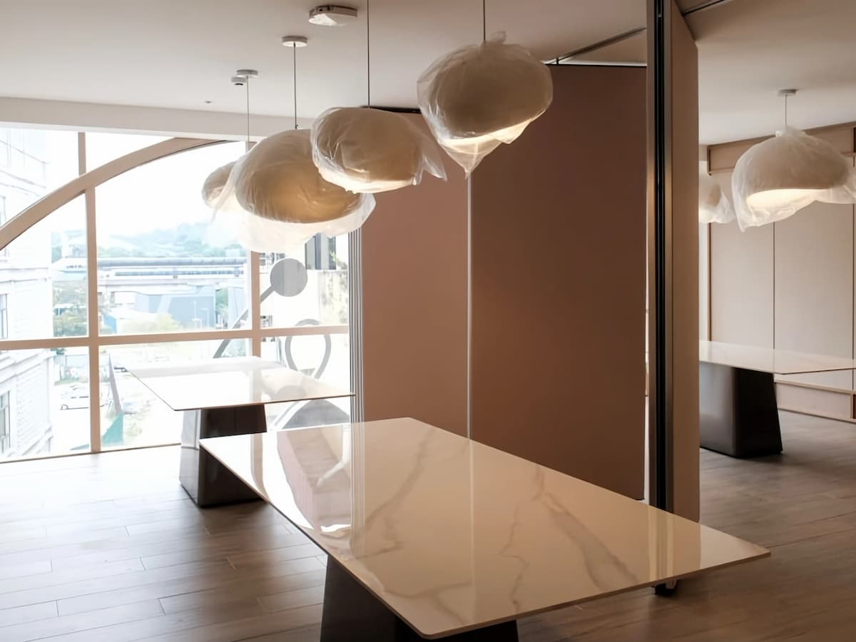 Minimalist private dining or meeting room with marble table, sculptural pendant lights, and floor-to-ceiling windows.