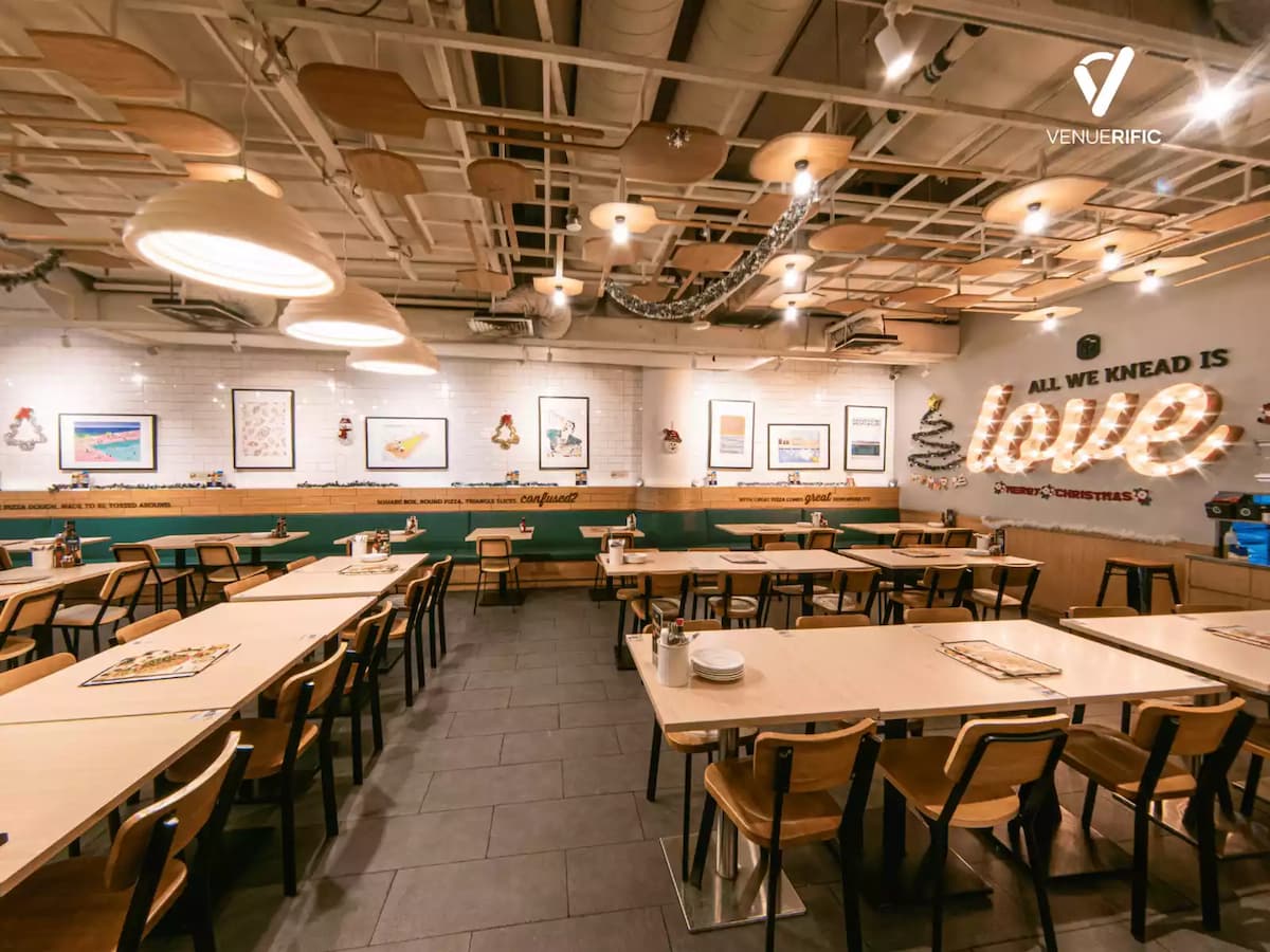 Bright Peperoni Suntec City dining area with wooden tables, modern ceiling lights, framed wall art, and ‘All We Knead Is Love’ feature wall.