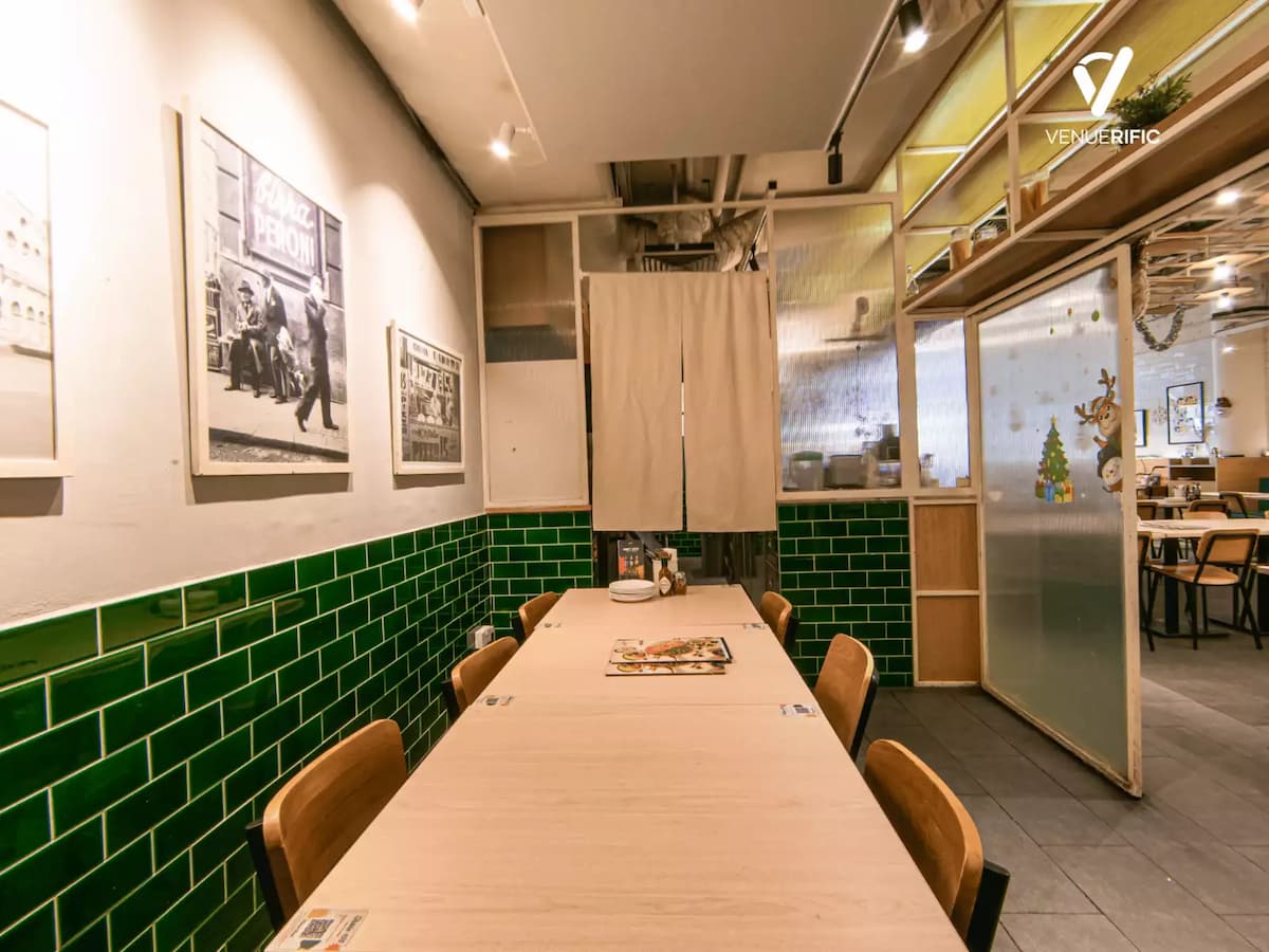 Private dining table with wooden seating, green tiled walls, framed vintage photos, and soft ambient lighting.