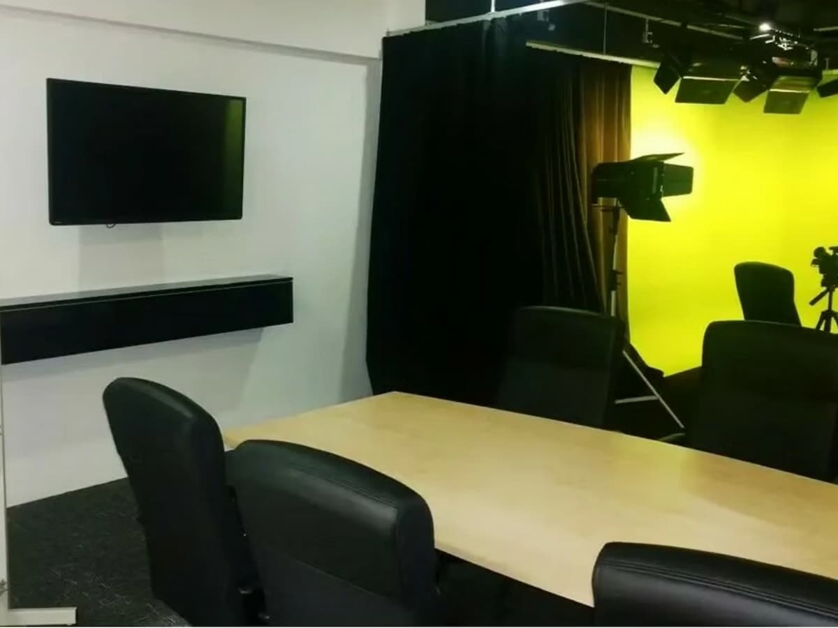 meeting table with black chairs and a wall mounted television beside the studio floor at an affordable corporate event space in kuala lumpur