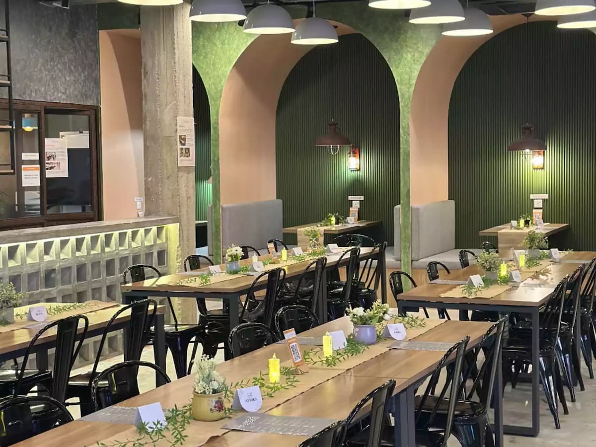 long wooden banquet tables set with candles and greenery at an industrial event space in bandar sunway