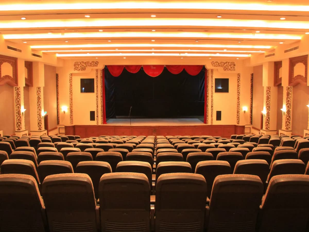 Traditional auditorium theatre with tiered seating and a stage framed by red curtains—ideal for performances, conferences, presentations, and large audience events.