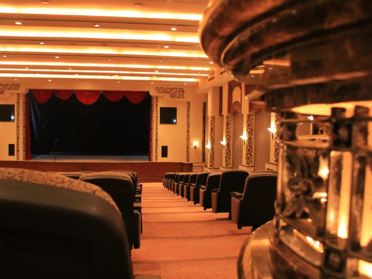 Traditional auditorium theatre with tiered seating and a stage framed by red curtains—ideal for performances, conferences, presentations, and large audience events.