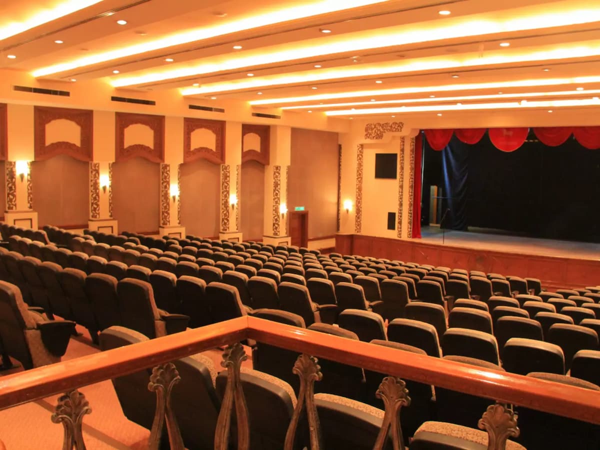 Traditional auditorium theatre with tiered seating and a stage framed by red curtains—ideal for performances, conferences, presentations, and large audience events.