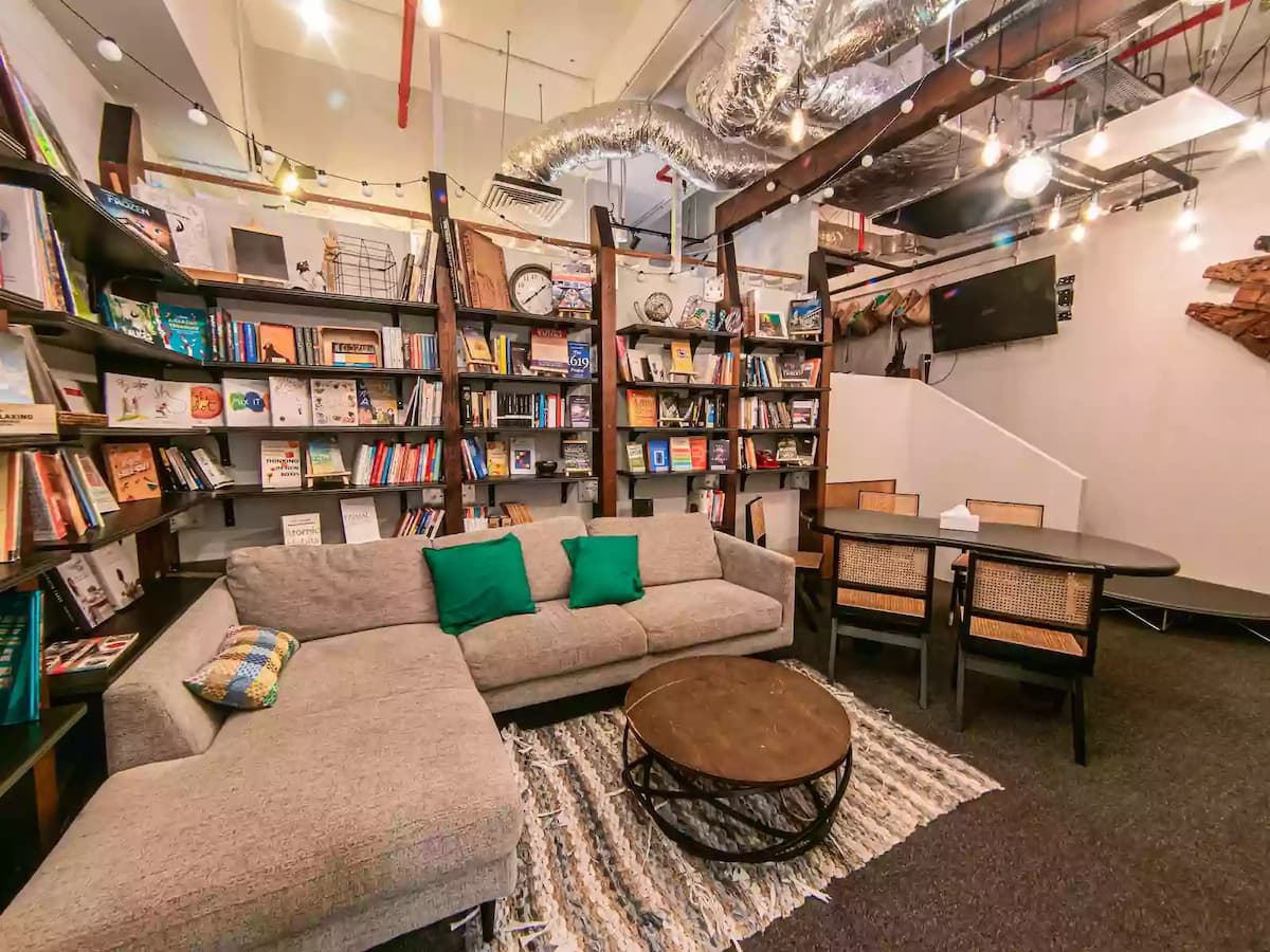 Warm and cozy creative lounge featuring bookshelves, sofa seating, and a small meeting table—ideal for team discussions, workshops, brainstorming sessions, book clubs, or intimate community gatherings.