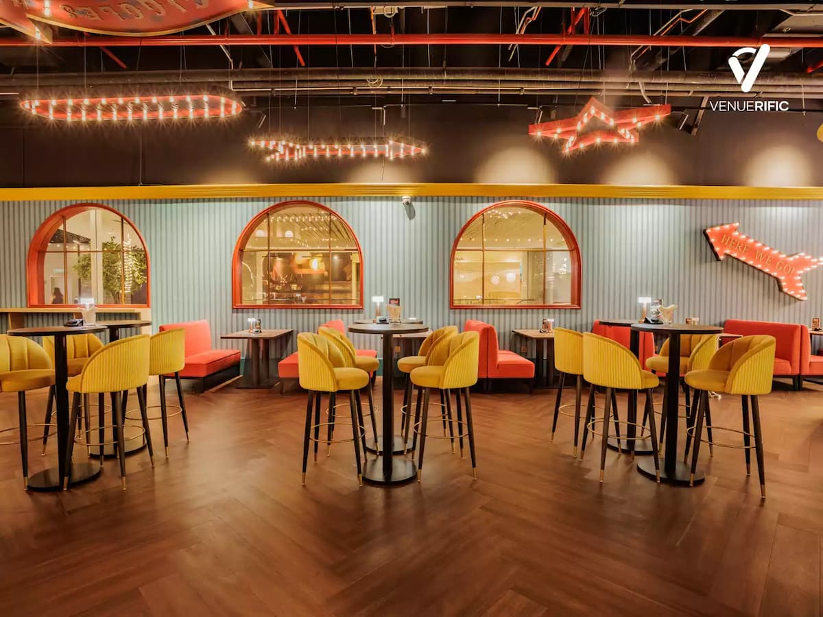 Spacious dining area with colorful seating, arched windows, and warm marquee lighting for lively gatherings.
