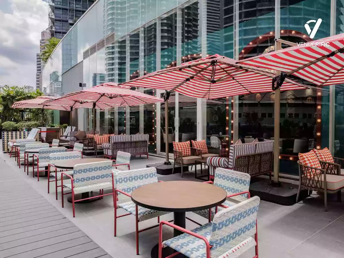 Outdoor terrace with striped umbrellas, patterned seating, and city skyline views for relaxed gatherings.