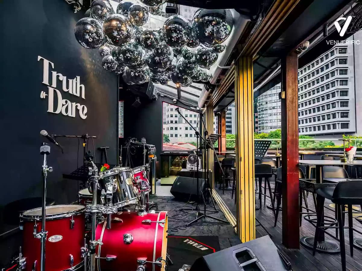 Live performance corner with drum set, disco ball ceiling, and terrace seating overlooking the city skyline.