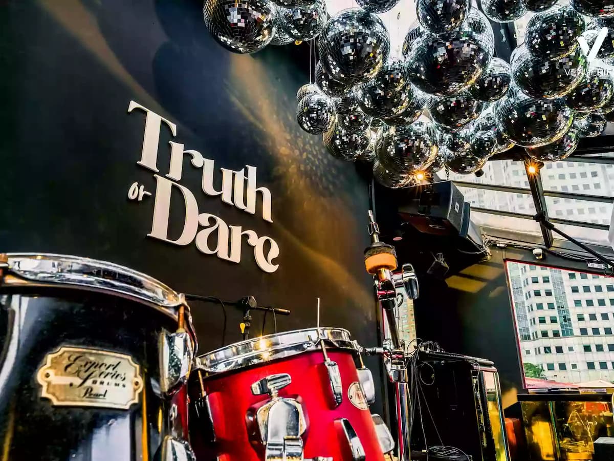 Close-up of a live performance stage with drum set, disco ball ceiling, and “Truth or Dare” backdrop.