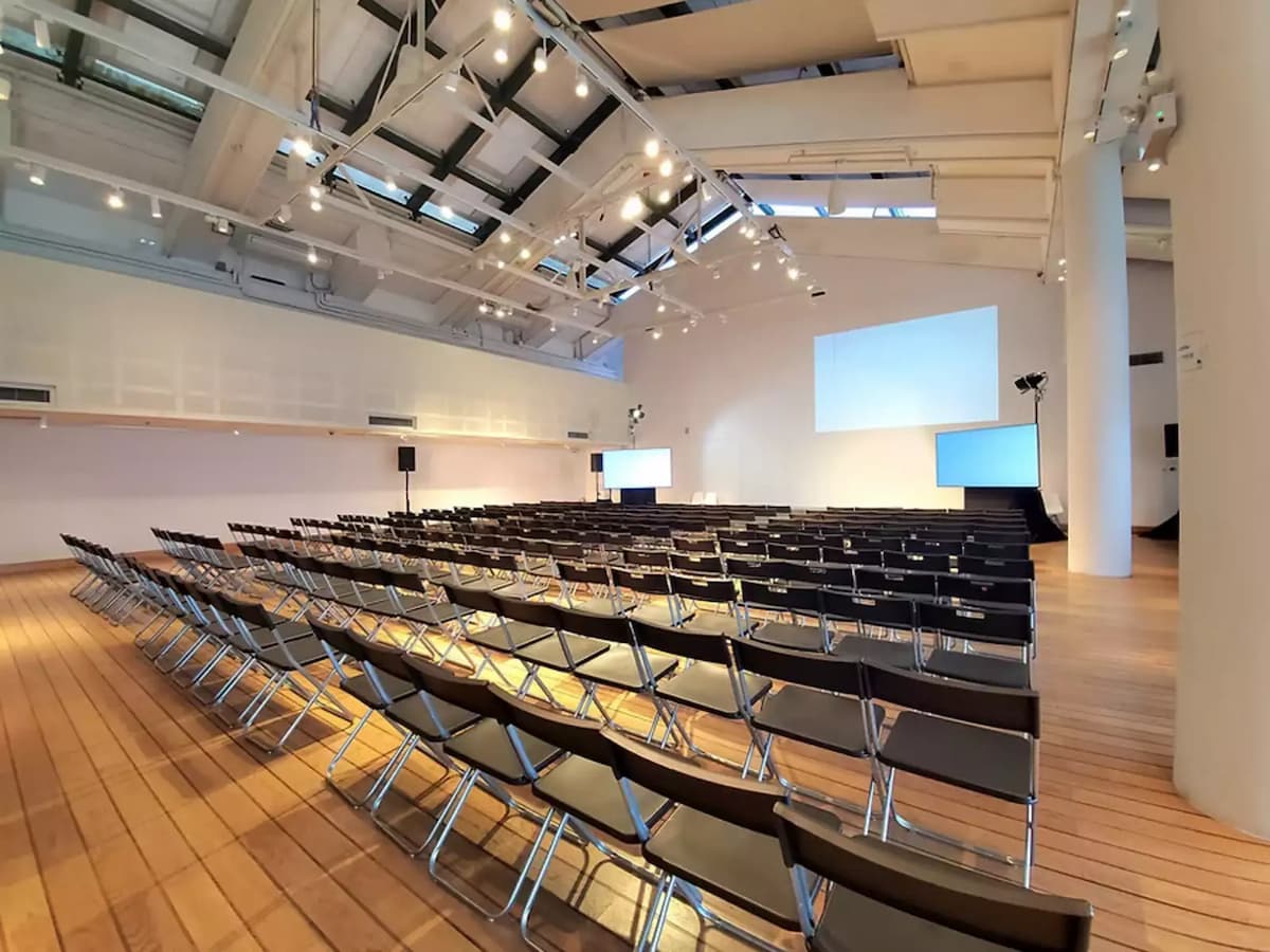 rows of black chairs facing projector screens at a conference event venue in hong kong maritime museum central