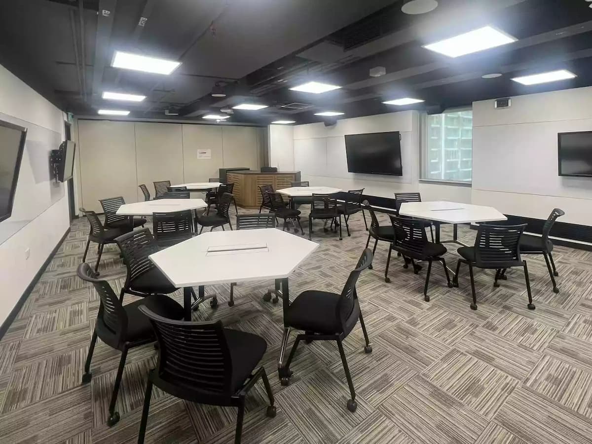 Modern training room setup with tables, chairs, and display screens.