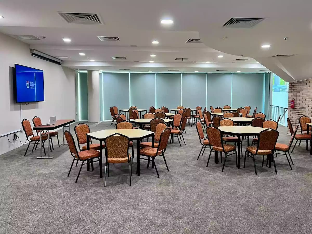 Event room setup with round tables, chairs, and presentation screen.