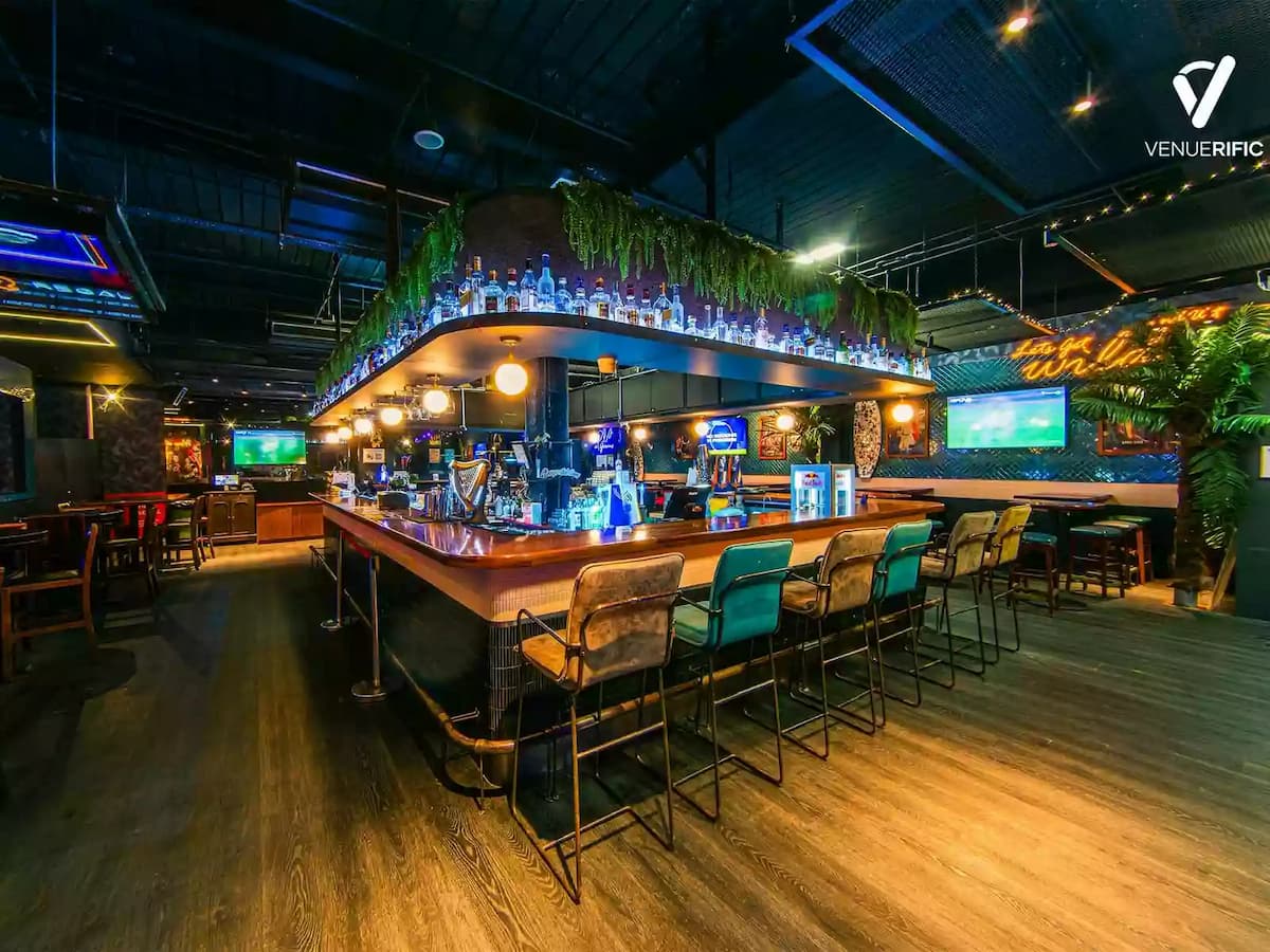 Modern bar area with high chairs and ambient lighting.