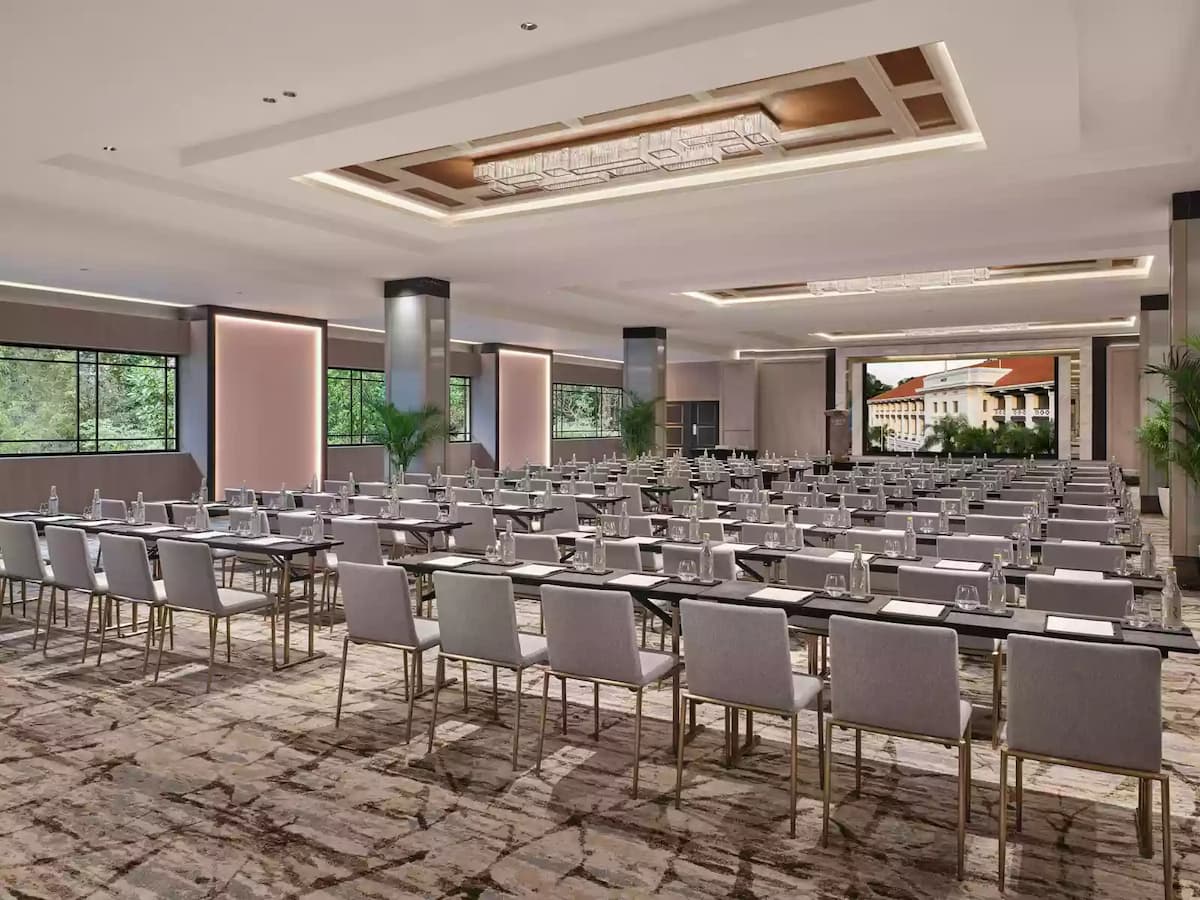 Large conference ballroom set in classroom style with rows of tables, grey chairs, and a projection screen