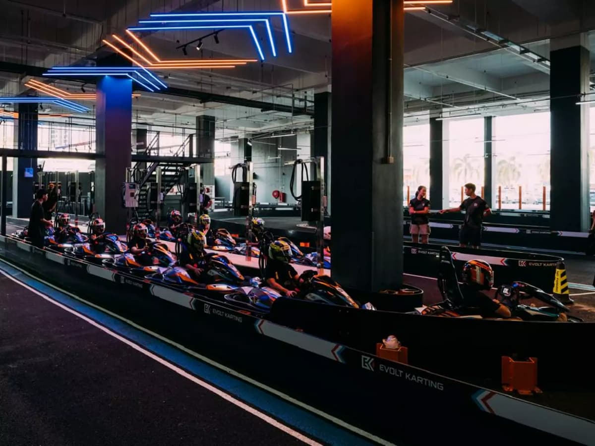 Electric go-karts lined up on the pre-race grid beneath neon lighting, ready for the next indoor racing session.