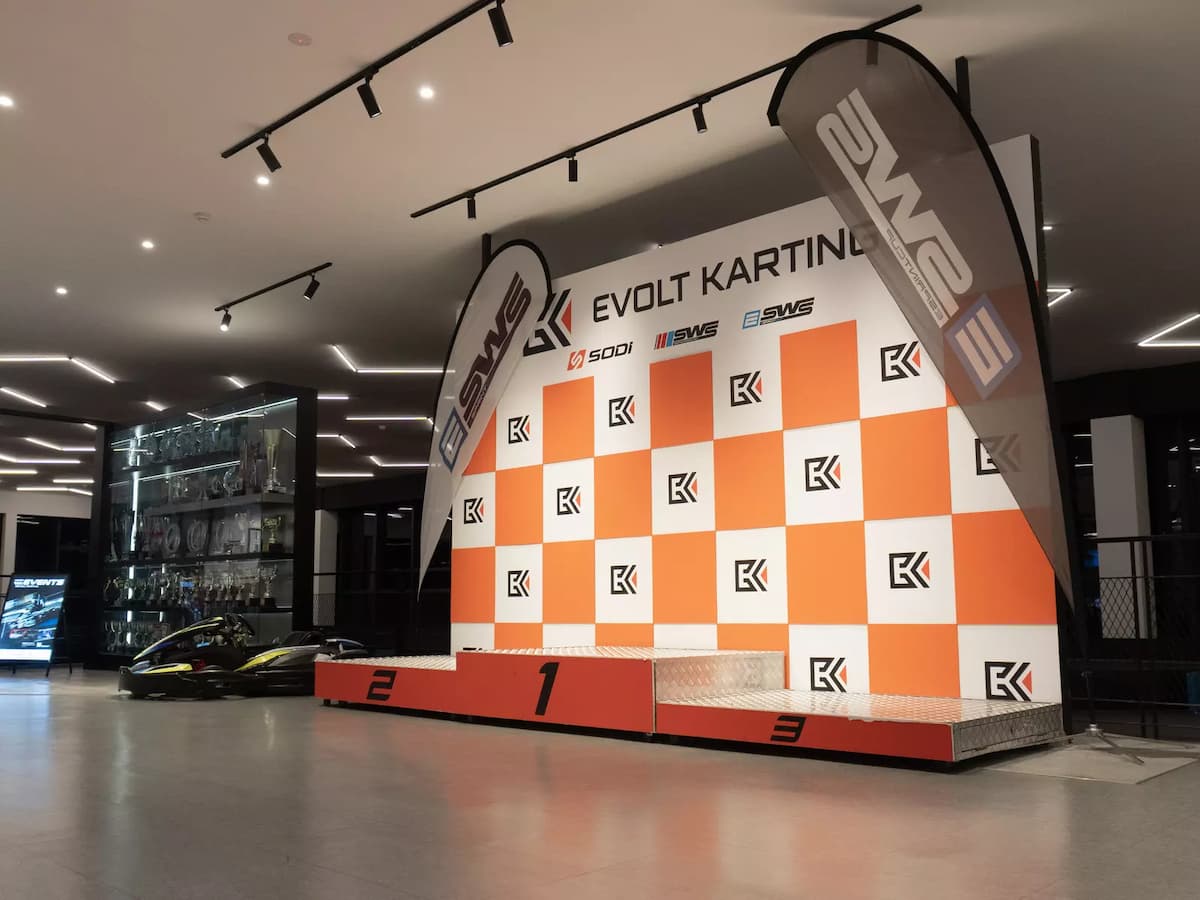 Winner's podium with branded photo backdrop, racing flags, and display area for post-race celebrations.