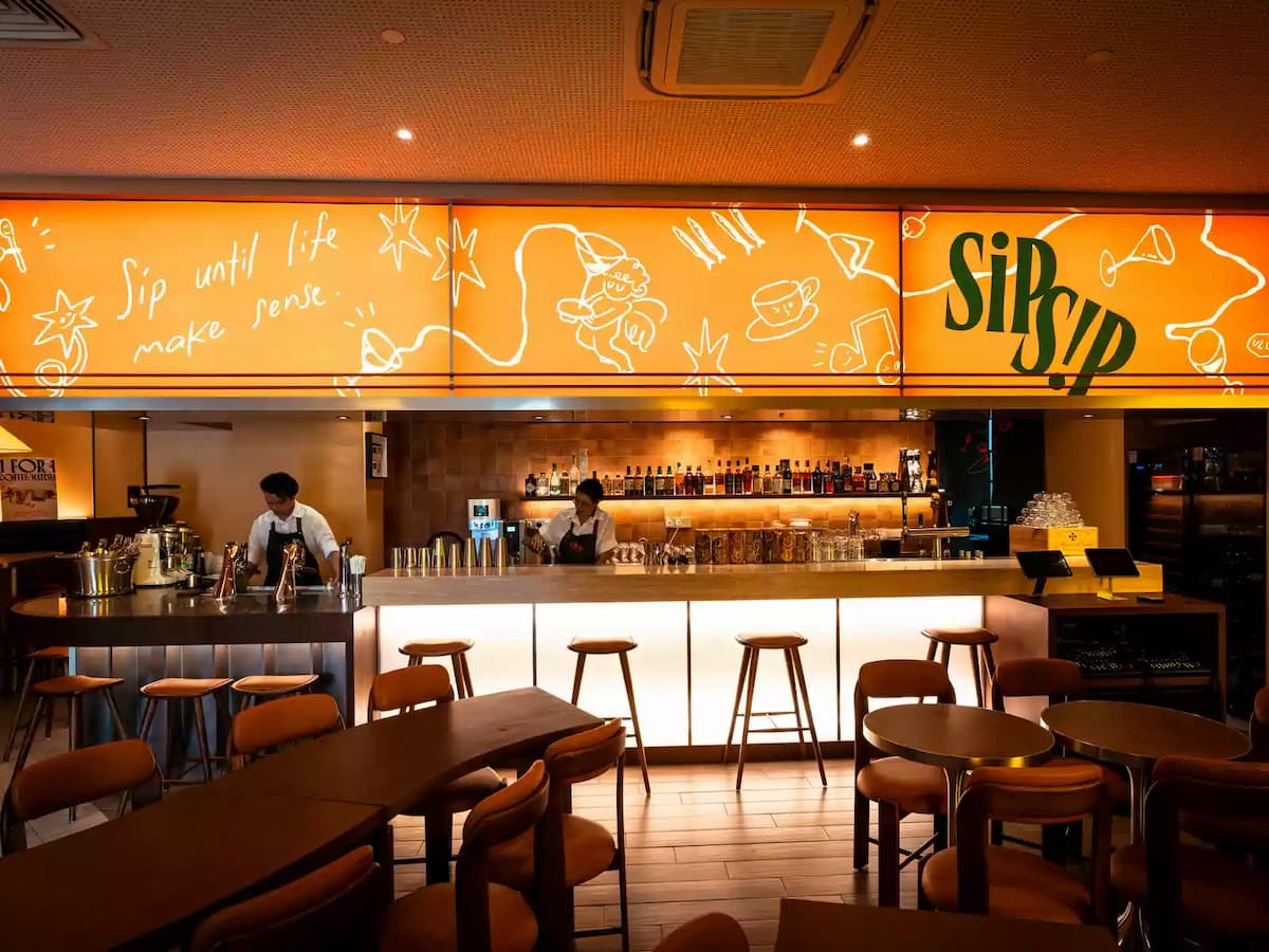 Contemporary bar counter with stylish seating, illuminated Sip Sip signage, and a welcoming space for cocktails and social gatherings.