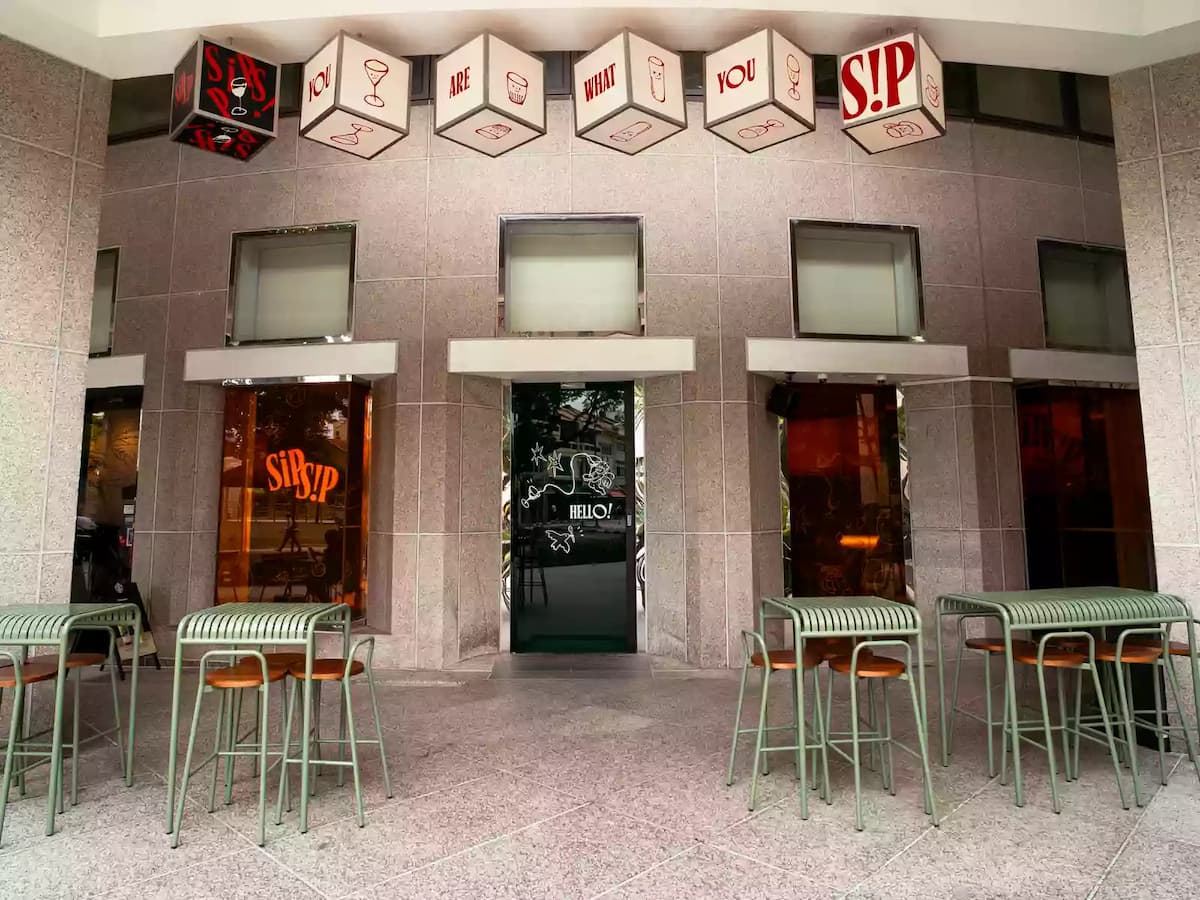 Modern Sip Sip restaurant entrance with outdoor high tables, bar seating, and welcoming storefront signage.