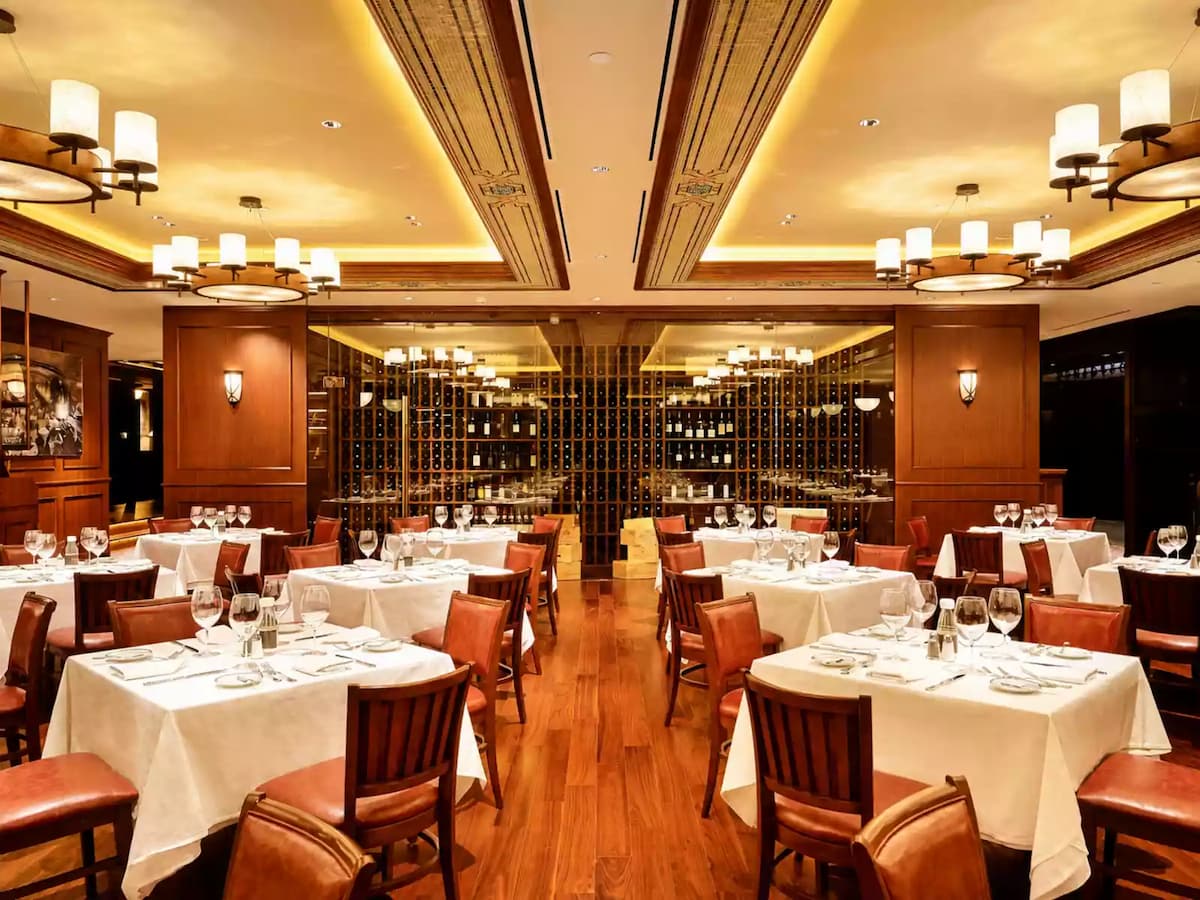 Elegant main dining room with premium table settings, an extensive wine display, and warm wood-panelled interiors.