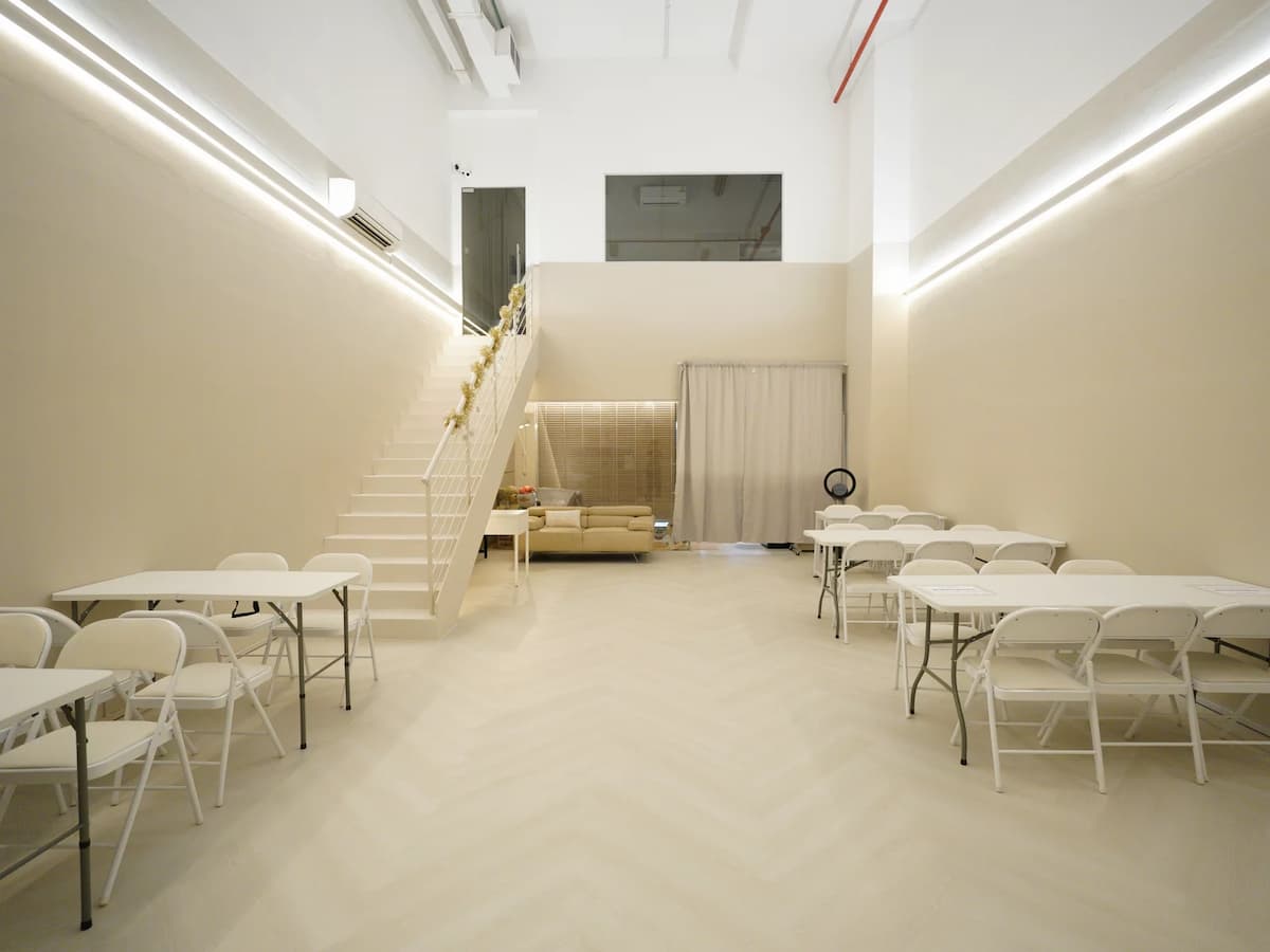 Spacious minimalist event venue with flexible table layouts, mezzanine lounge, and adaptable space for workshops, training sessions, meetings, and private events.