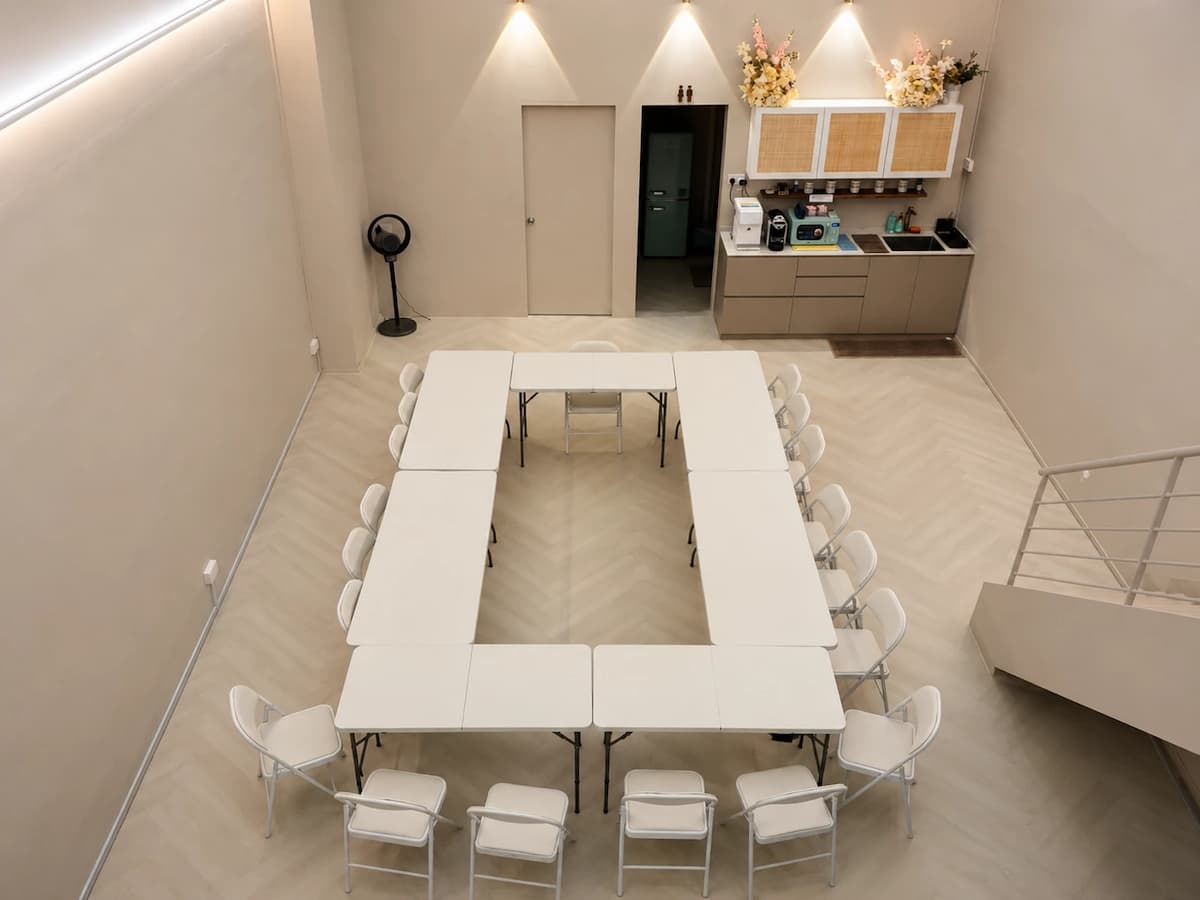 Bright minimalist event space arranged in a U-shaped boardroom layout with pantry facilities, ideal for workshops, meetings, training sessions, and collaborative discussions.