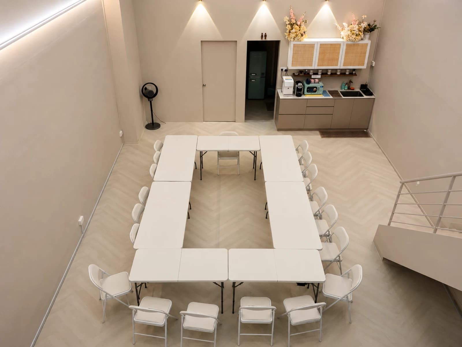 Bright minimalist event space arranged in a U-shaped boardroom layout with pantry facilities, ideal for workshops, meetings, training sessions, and collaborative discussions.