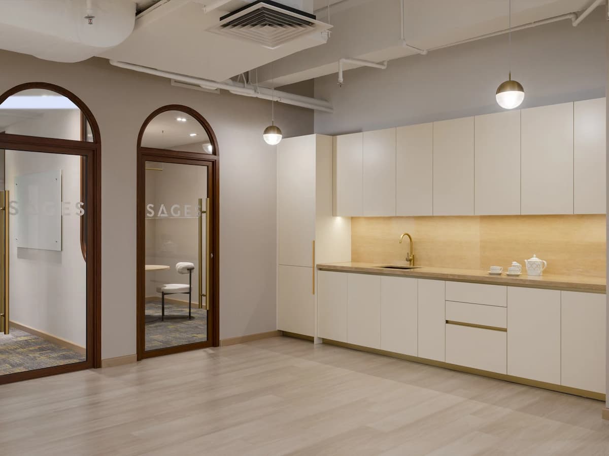 Modern event space with a built-in pantry, minimalist kitchenette, and adjoining meeting rooms, ideal for workshops, training sessions, corporate events, wellness classes, and private gatherings.