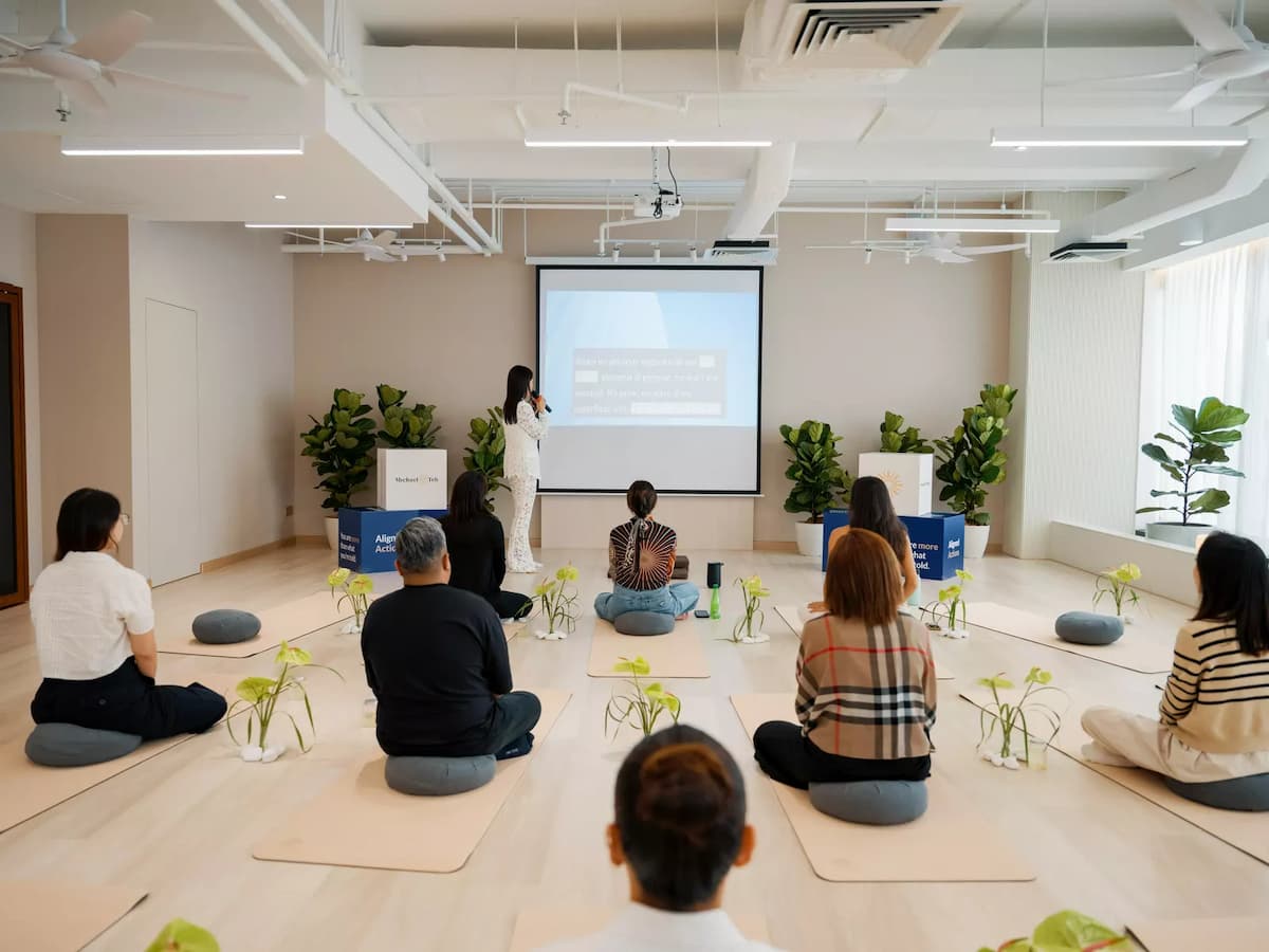 Bright multipurpose event space configured for a wellness seminar with projector, floor seating, and open-plan layout, ideal for workshops, mindfulness sessions, corporate training, presentations, and wellness events.