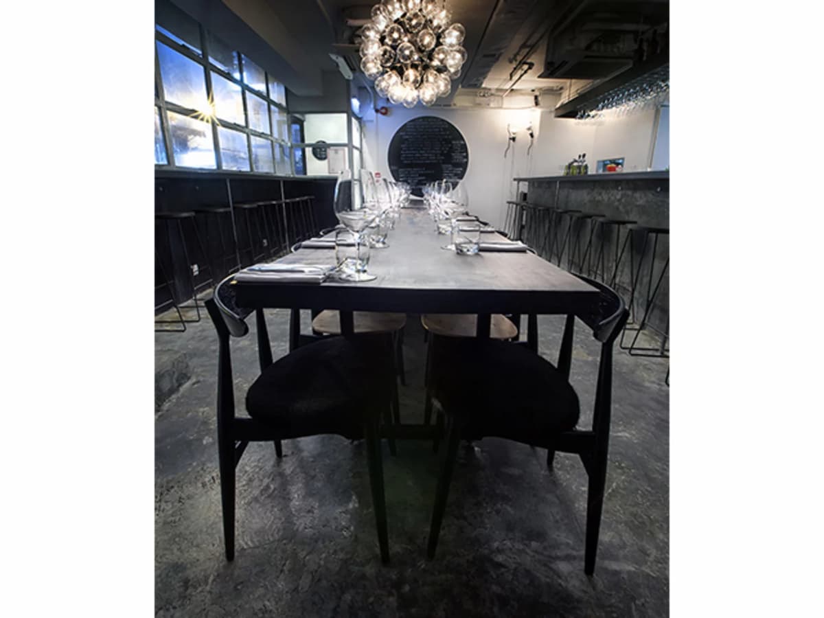private room with long wooden table and a few bar stools lining the bar