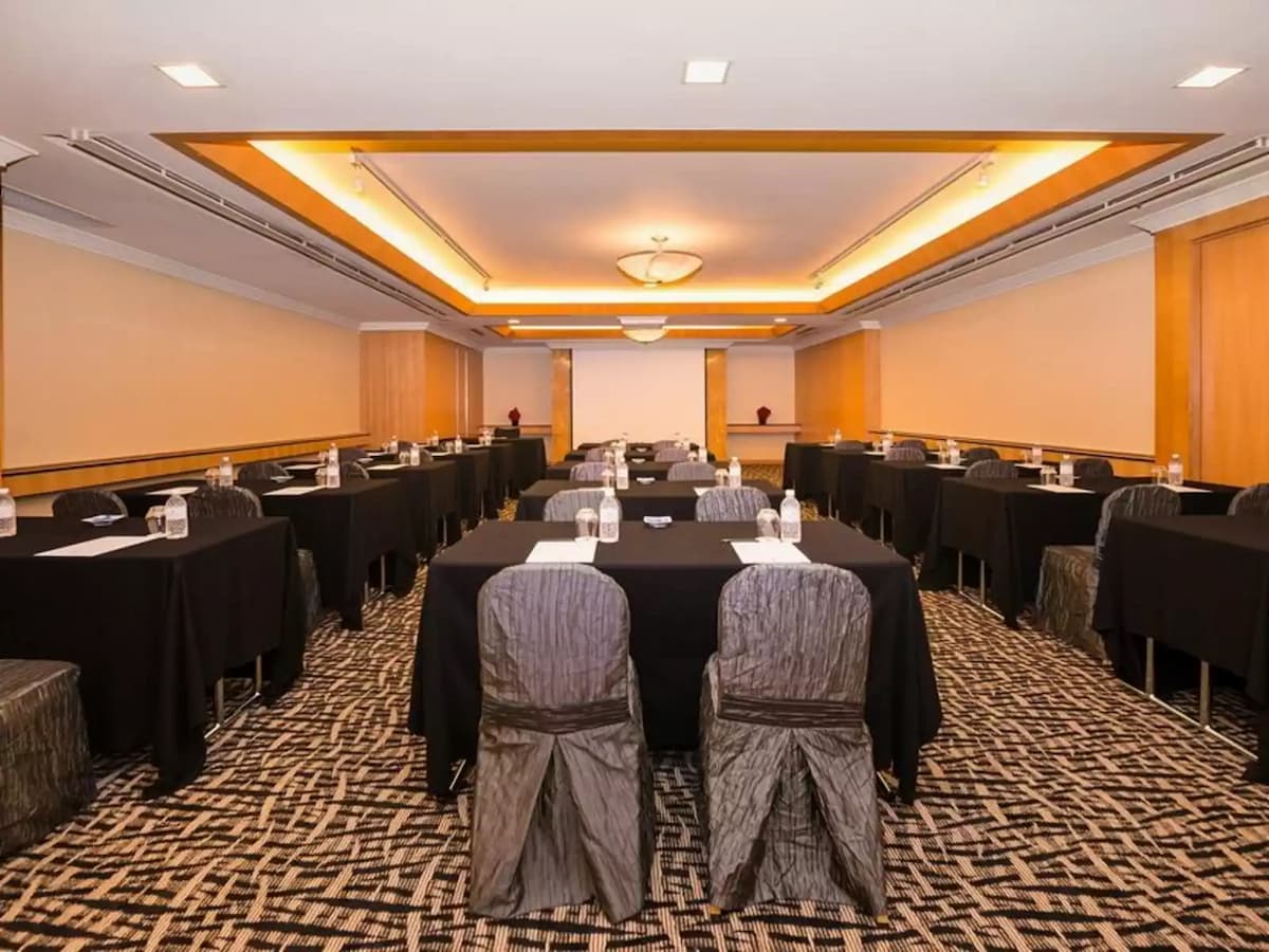 corporate hall with rows of chairs and tables and a projector