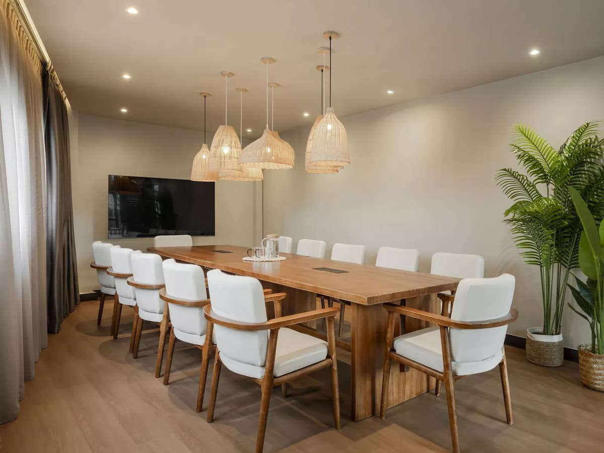modern meeting room with a long wooden table, white chairs, and a large TV screen