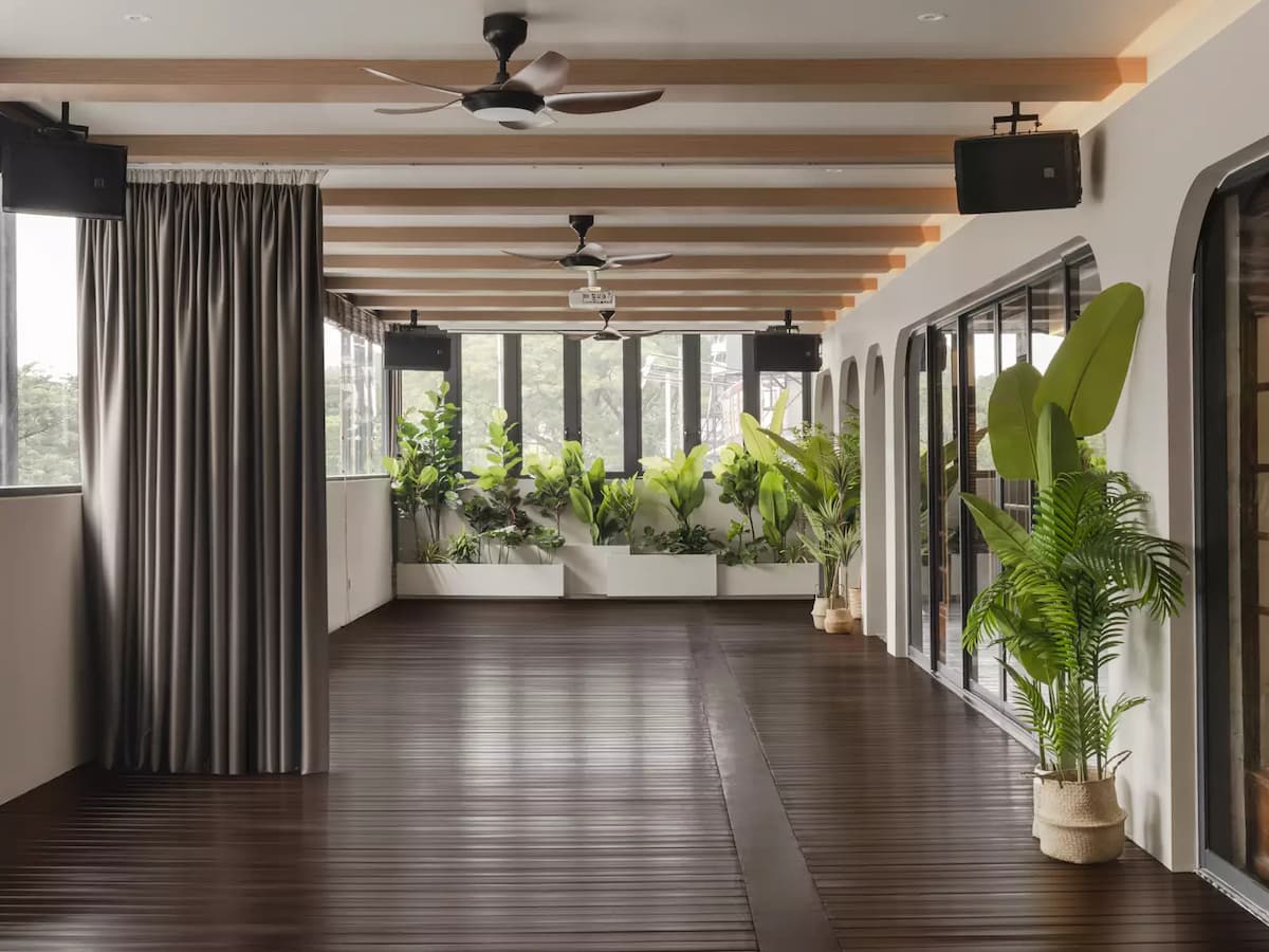 open-air room with a wooden floor, large windows, and potted plants