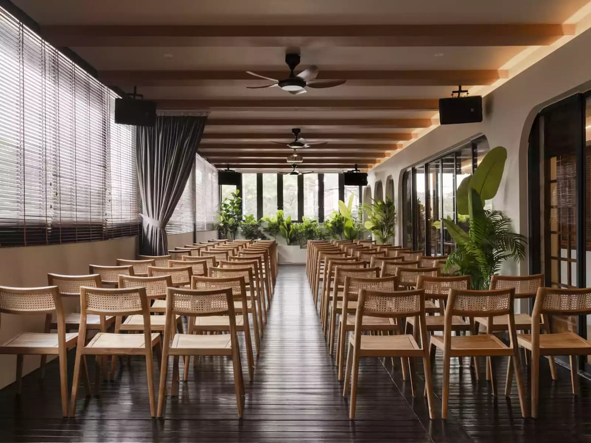 long row of wooden chairs arranged in a spacious room with large windows and a wooden ceiling