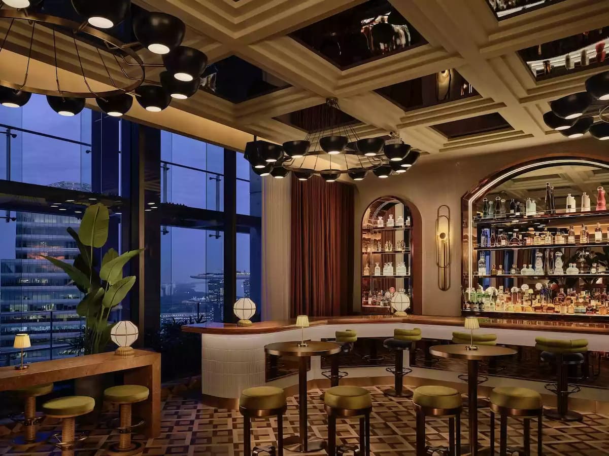 A stylish bar with panoramic city views featuring elegant green velvet seating