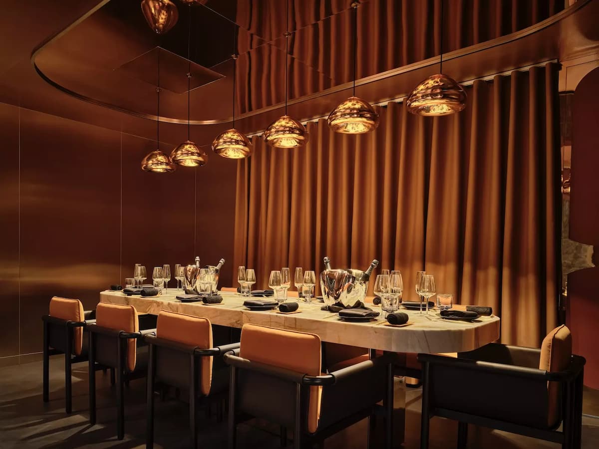 An intimate and luxurious private dining room featuring a sleek marble table under warm amber lighting