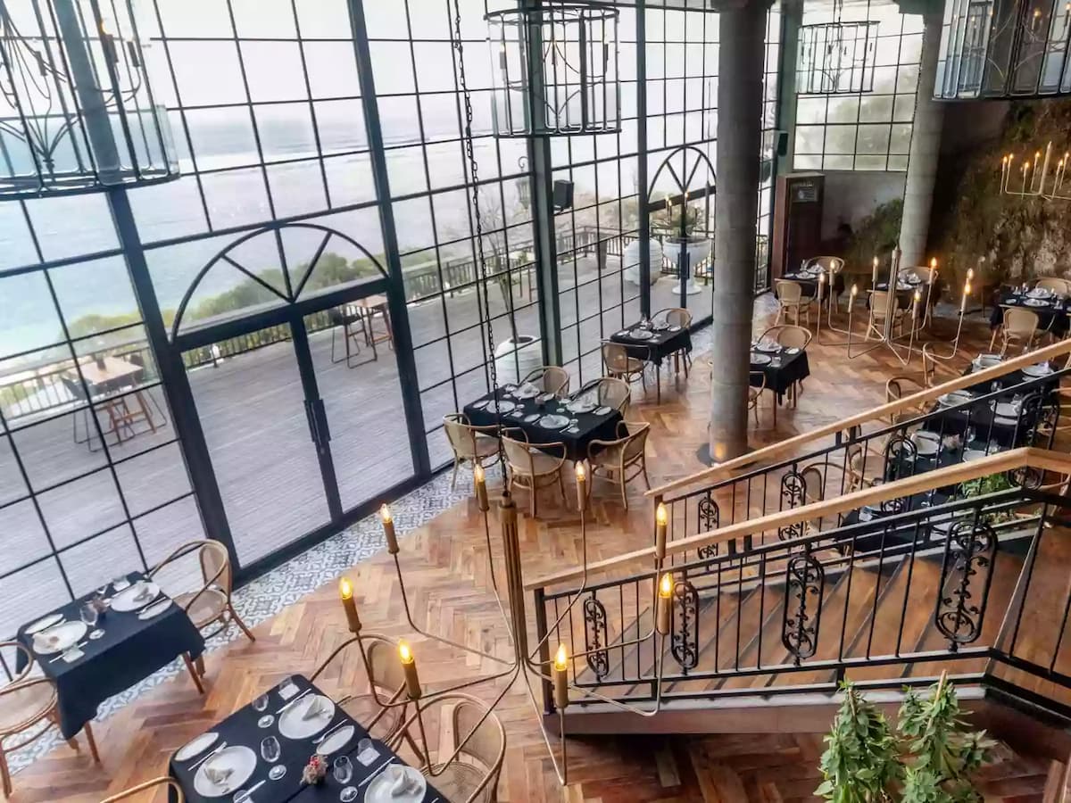 oceanfront dining space with floor-to-ceiling glass windows and elegant black table settings