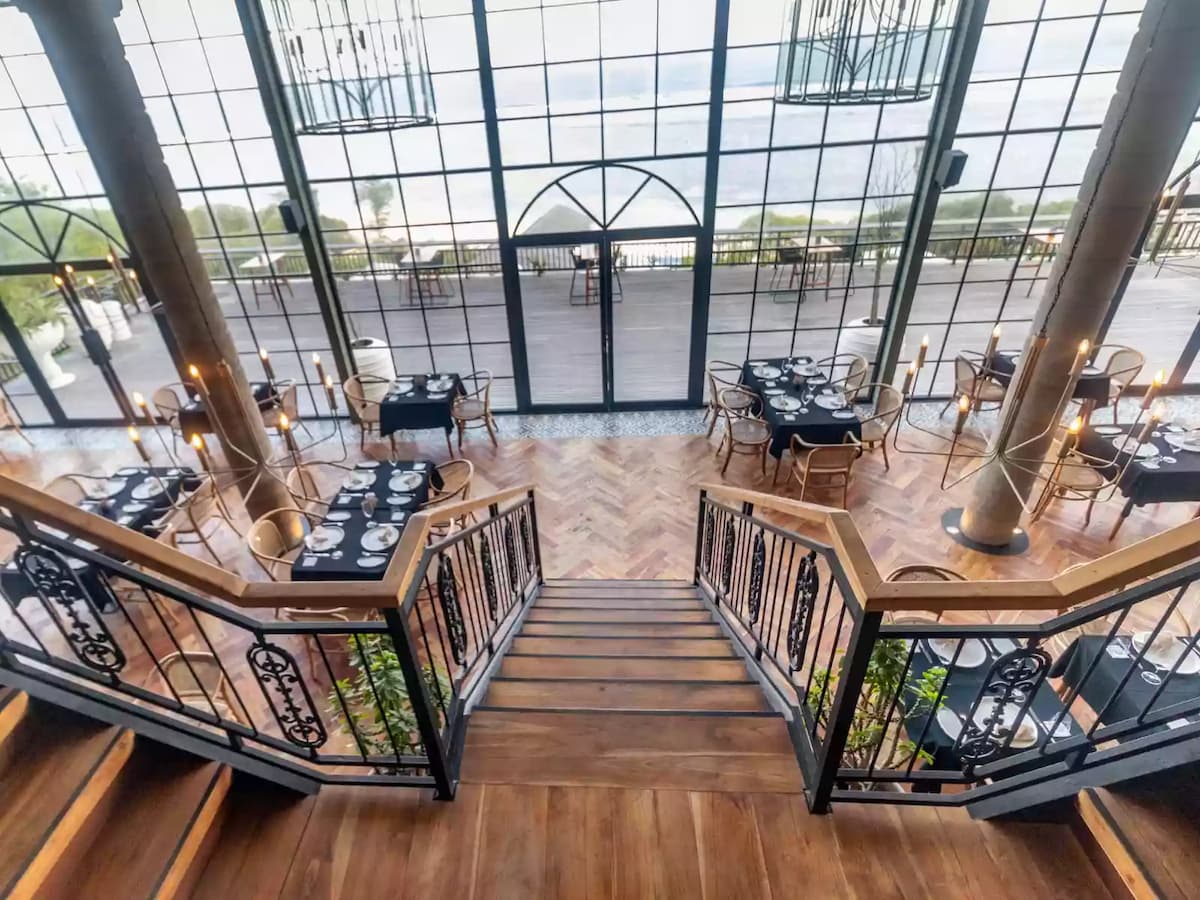 a grand staircase leads down to a luxurious oceanfront dining space