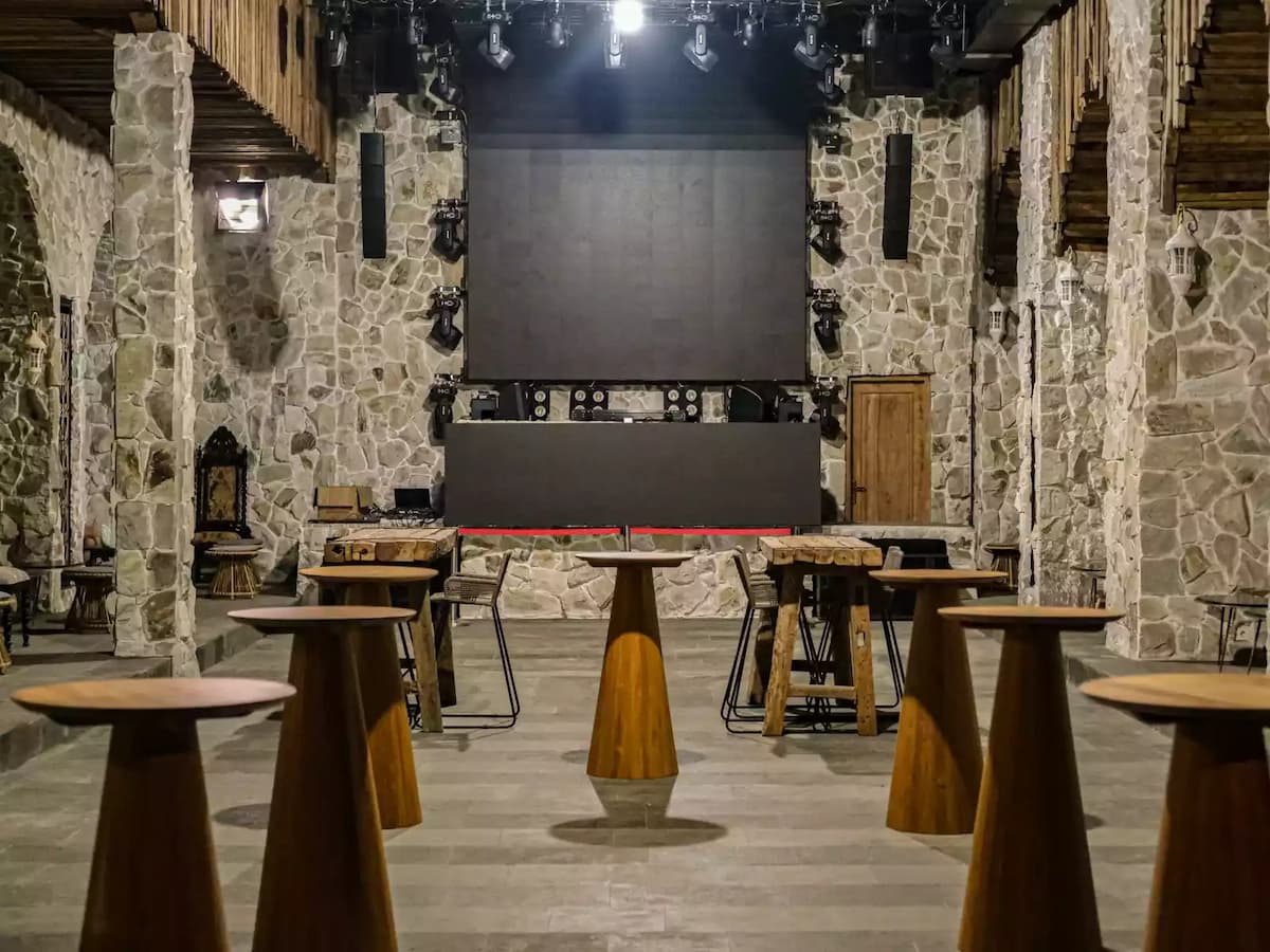 wooden high-top tables, and a central stage with a large screen