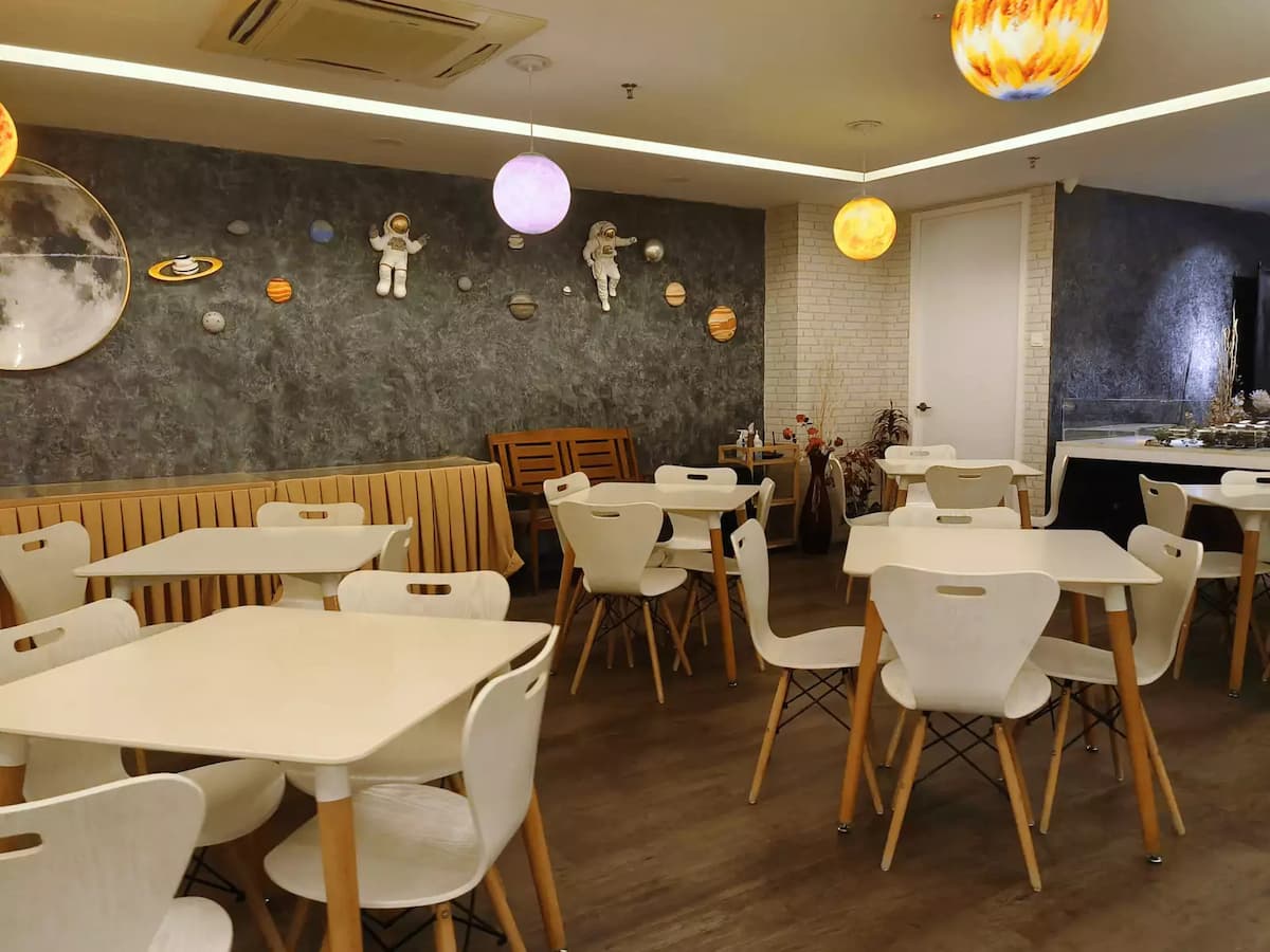 white tables and chairs, cosmic wall decorations featuring planets and astronauts