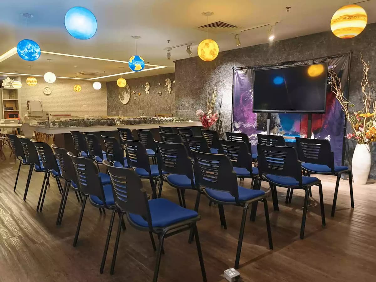 space-themed event hall set up with rows of black and blue chairs facing a large screen