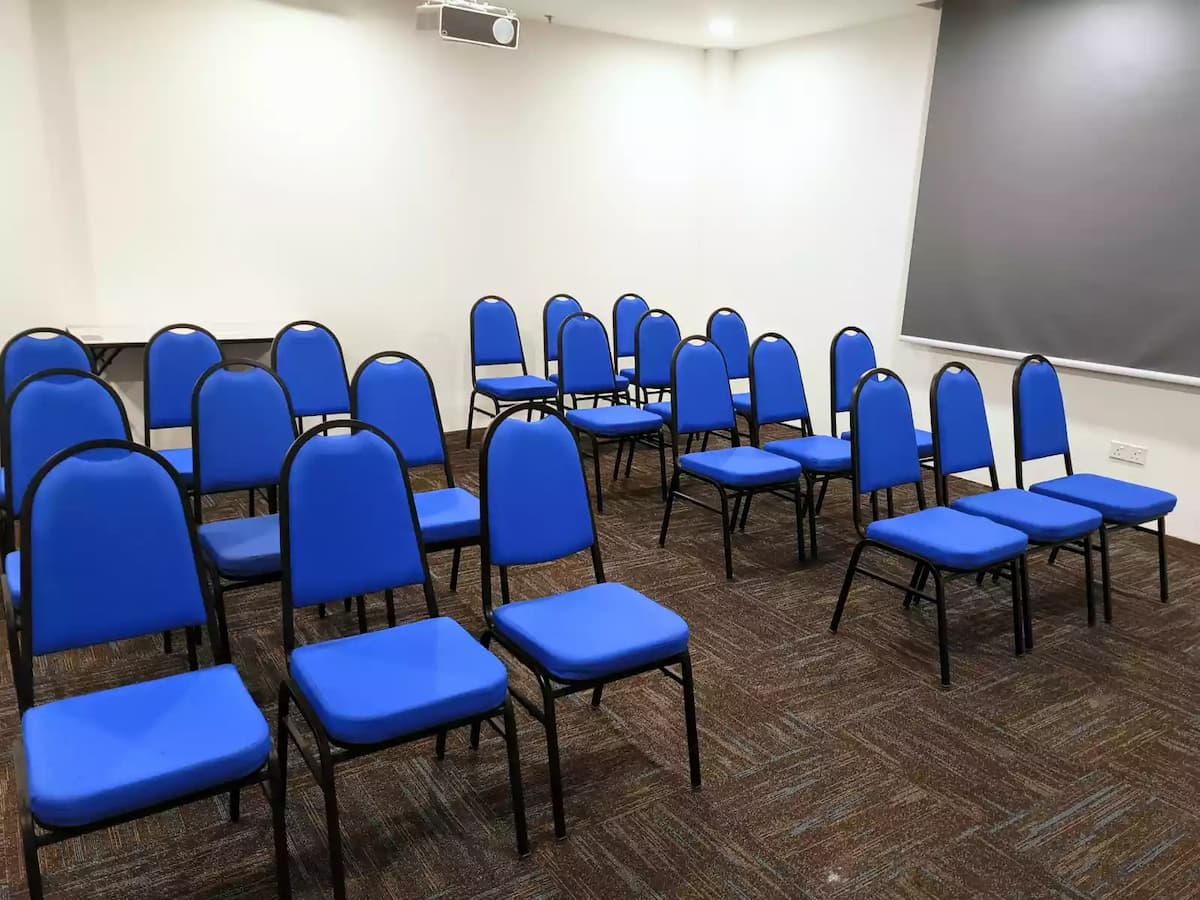A simple and functional seminar room featuring rows of blue cushioned chairs