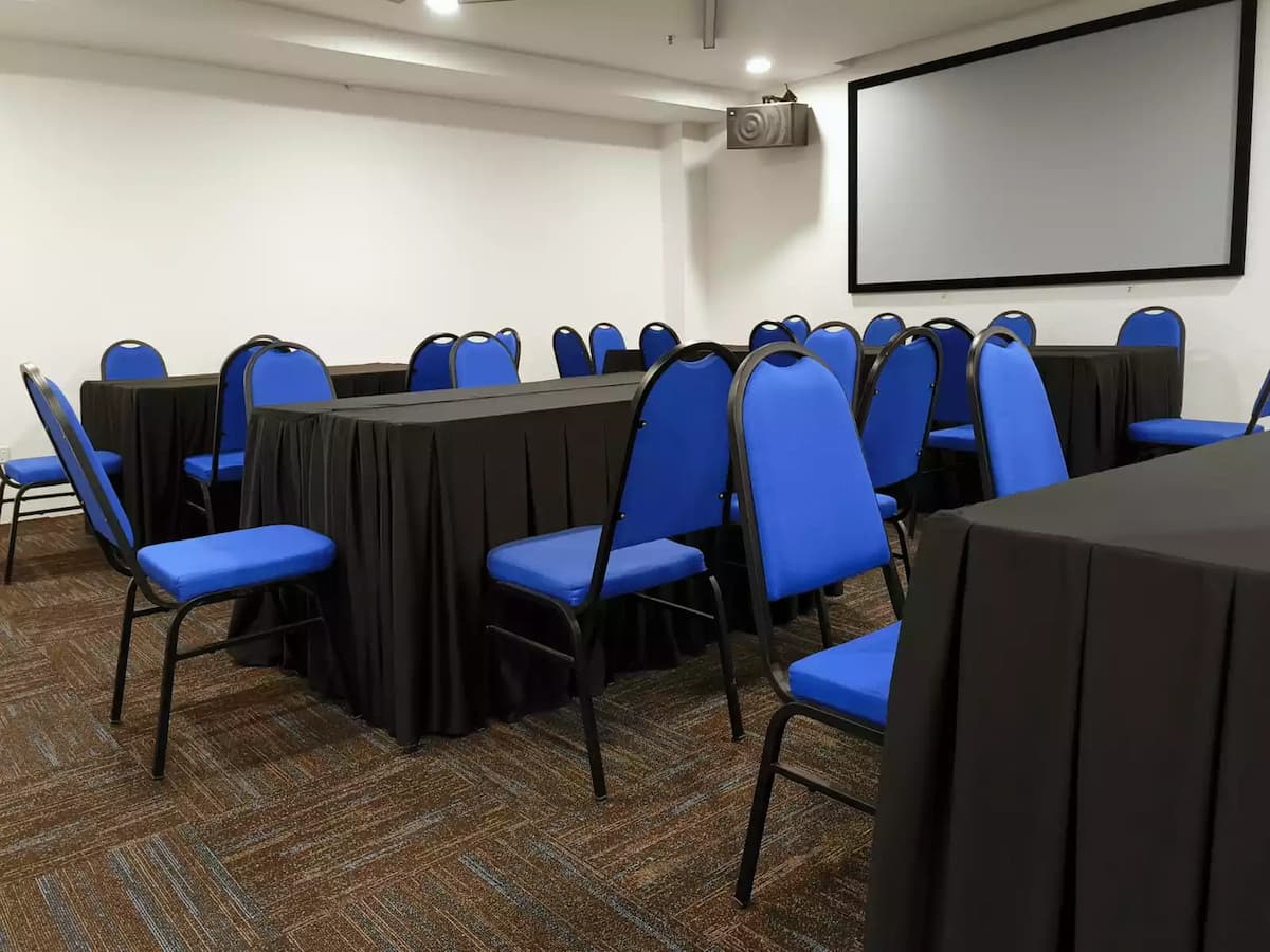 A professional room featuring blue cushioned chairs and tables with black covers