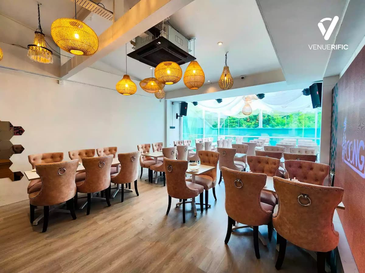 Chic event dining space with blush tufted chairs, marble-top tables, woven pendant lights, and floor-to-ceiling windows overlooking greenery.