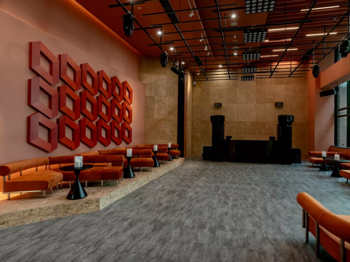 Modern lounge with curved velvet seating, black side tables, and bold red geometric wall art.