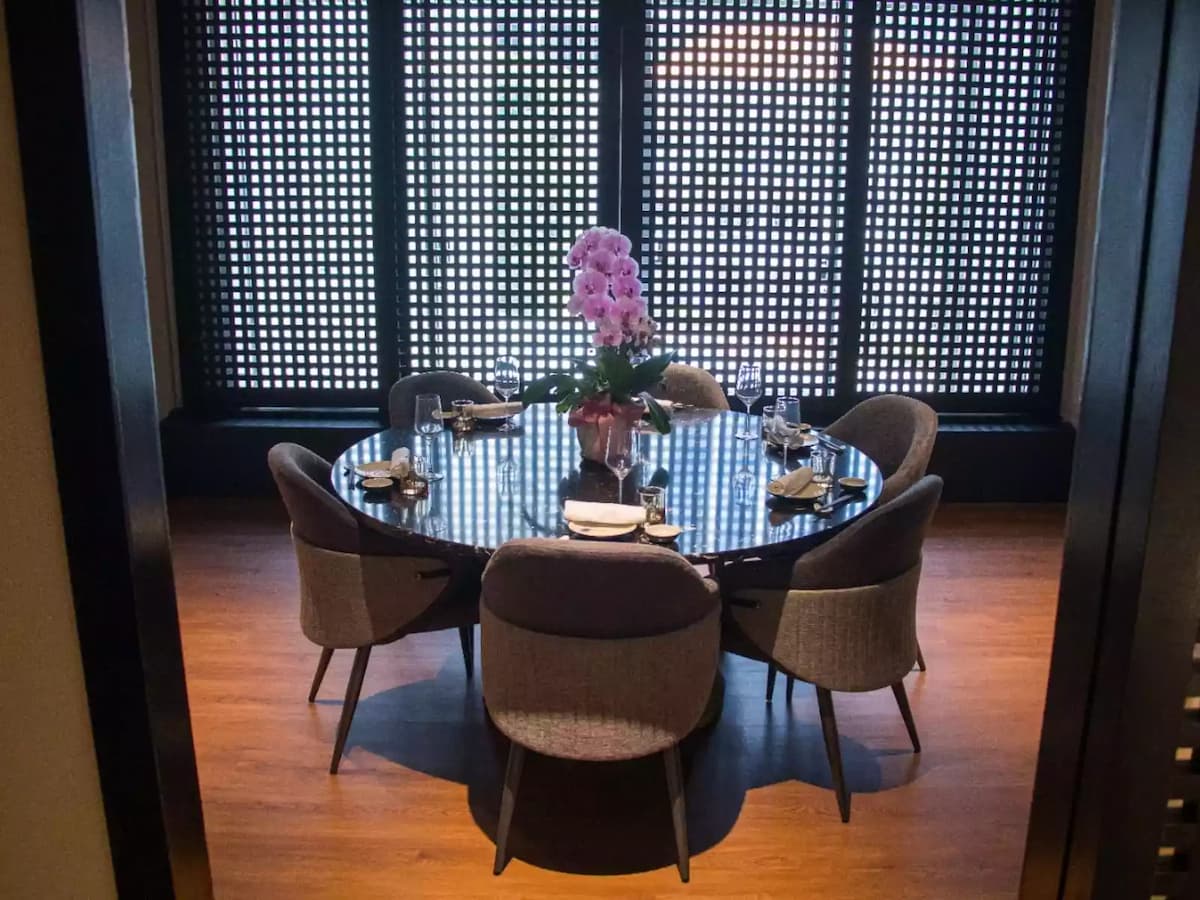A round black marble dining table for six with grey upholstered chairs