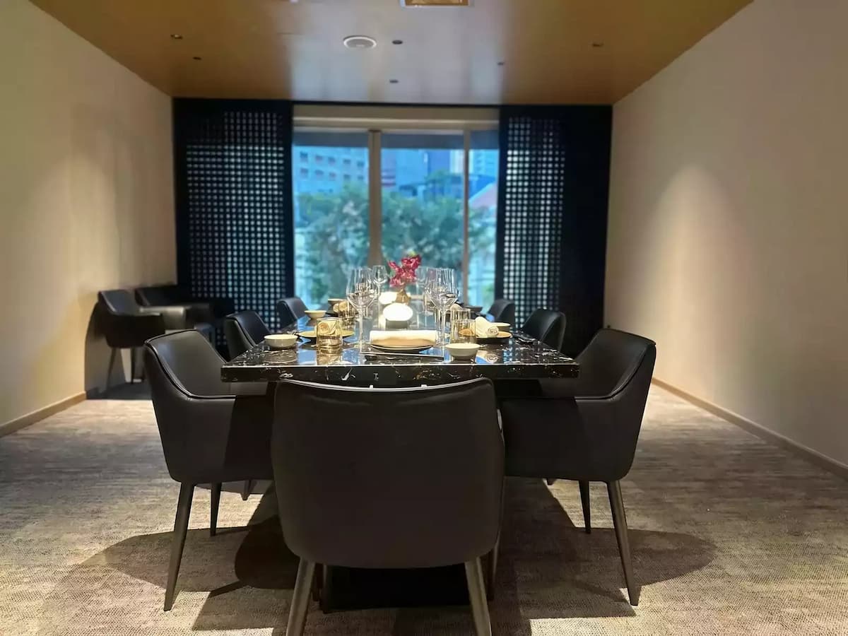 An elegant restaurant table with a dark, polished marble surface is set with fine crystal stemware and white linens.
